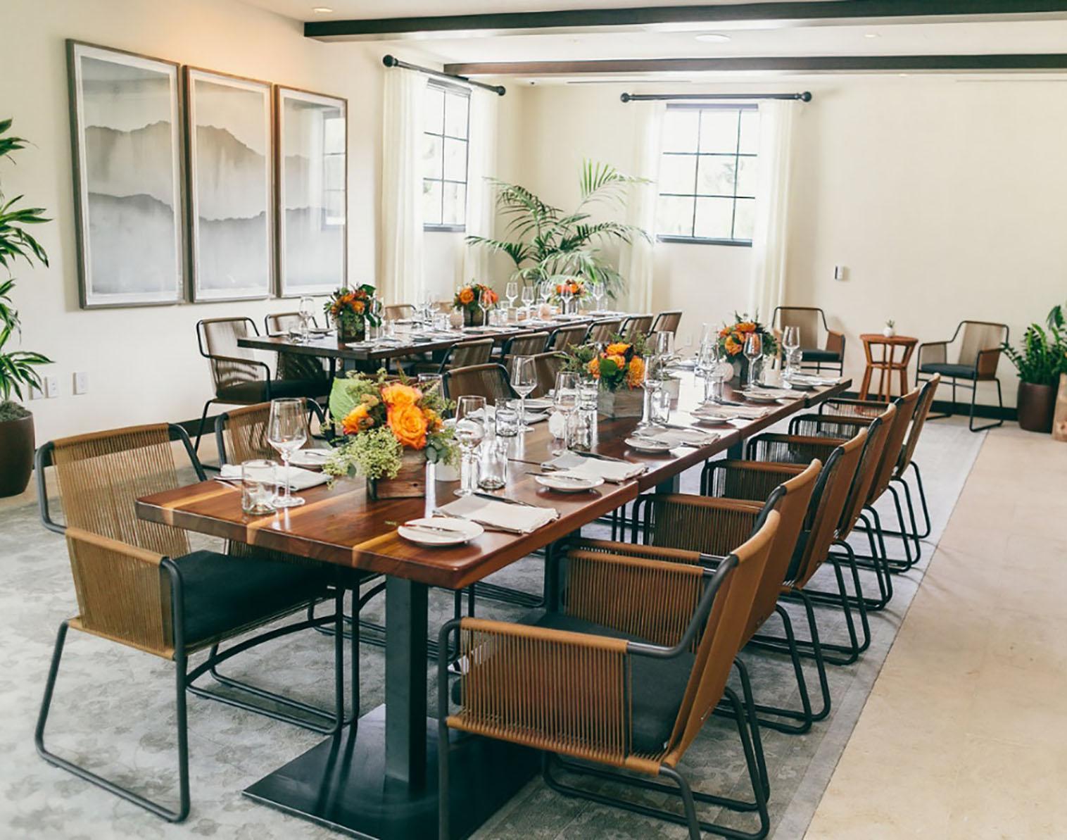 Elegant meeting space with long table and floral centerpieces for private events.