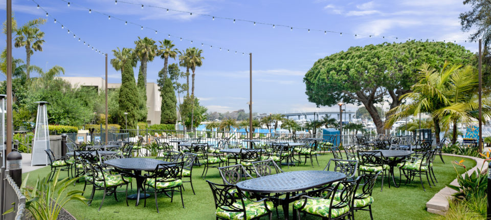 Outdoor event space at Firefly Eatery & Bar with lush greenery and string lights.