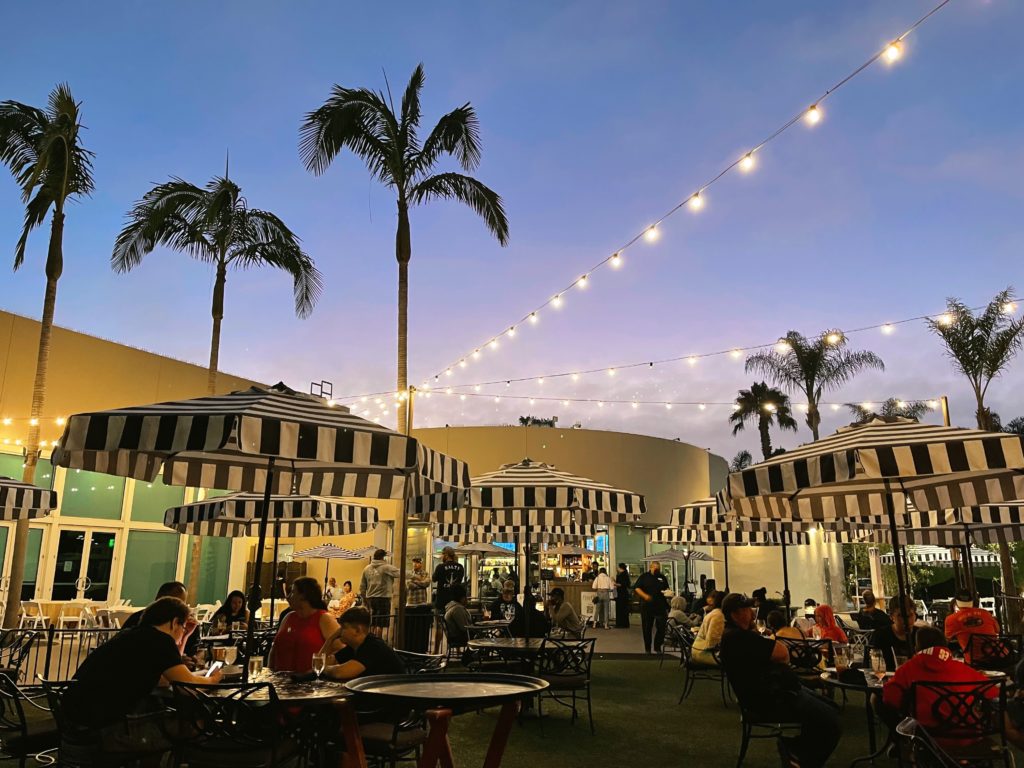 Firefly Eatery outdoor event space with striped umbrellas, perfect for gatherings and networking.