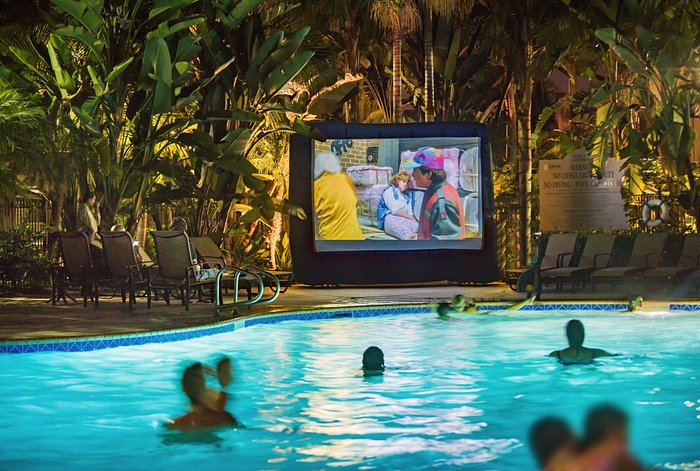Tropical Courtyard event with inflatable screen by pool for summer gatherings.