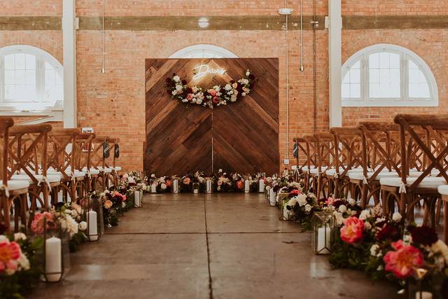 Elegant wedding ceremony setup in San Diego with floral aisle and wooden backdrop.