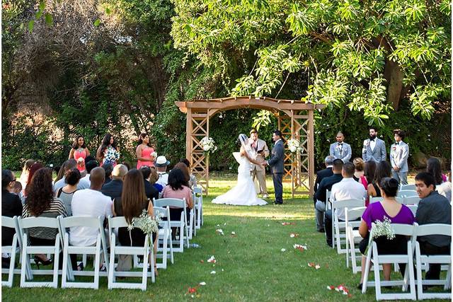 Outdoor wedding ceremony in Swiss Park with floral arch and lush greenery.