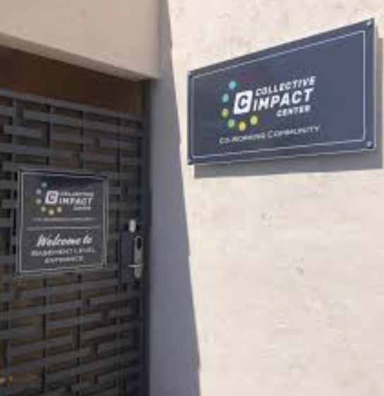 Shared desk at Collective Impact Center, modern signage for meetings and networking.