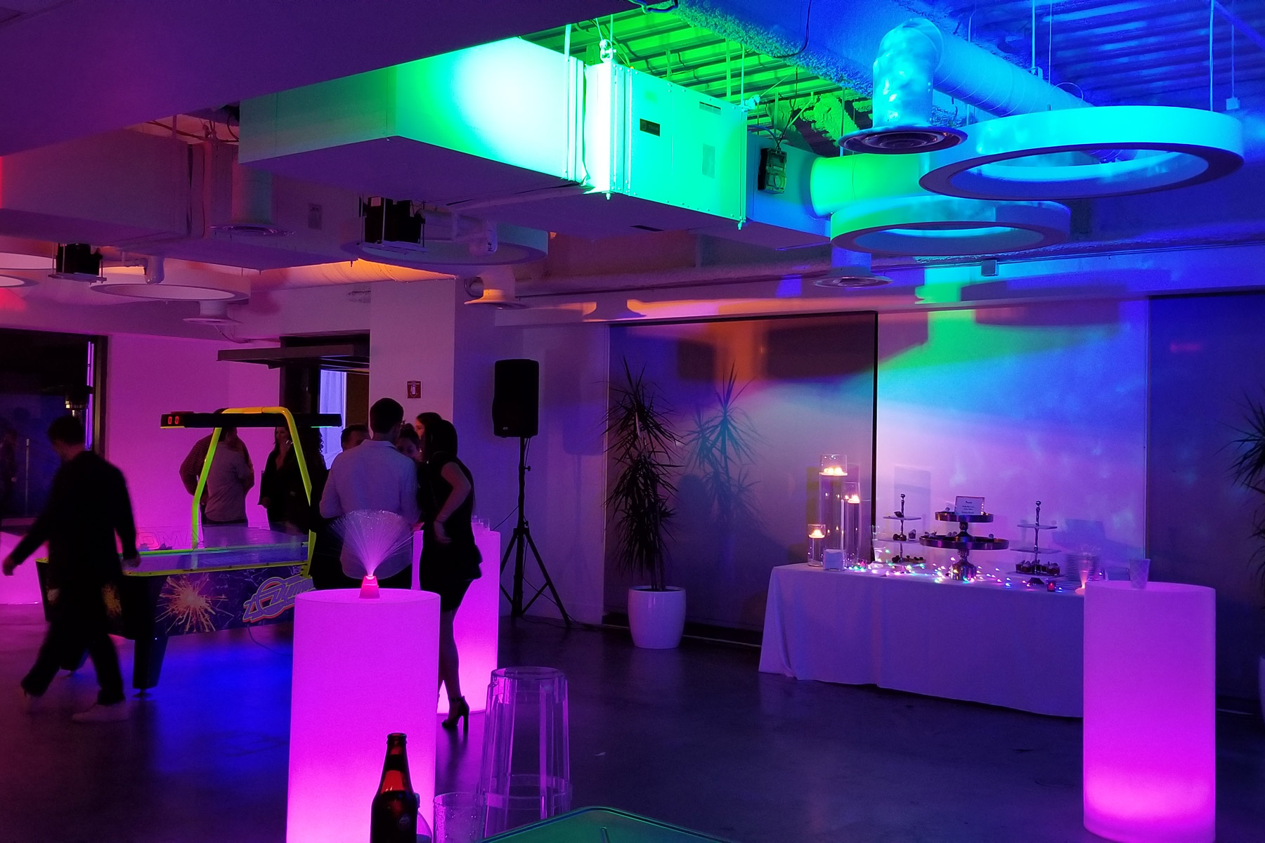 Vibrant wedding venue with modern decor and colorful uplighting for receptions.