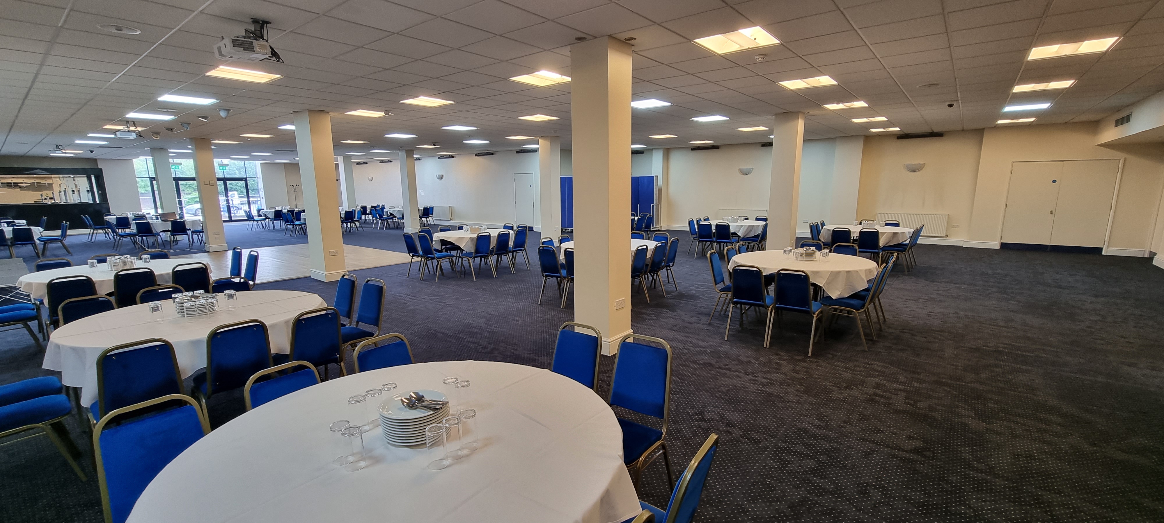 Saffron Suite conference venue with round tables and blue chairs for corporate events.