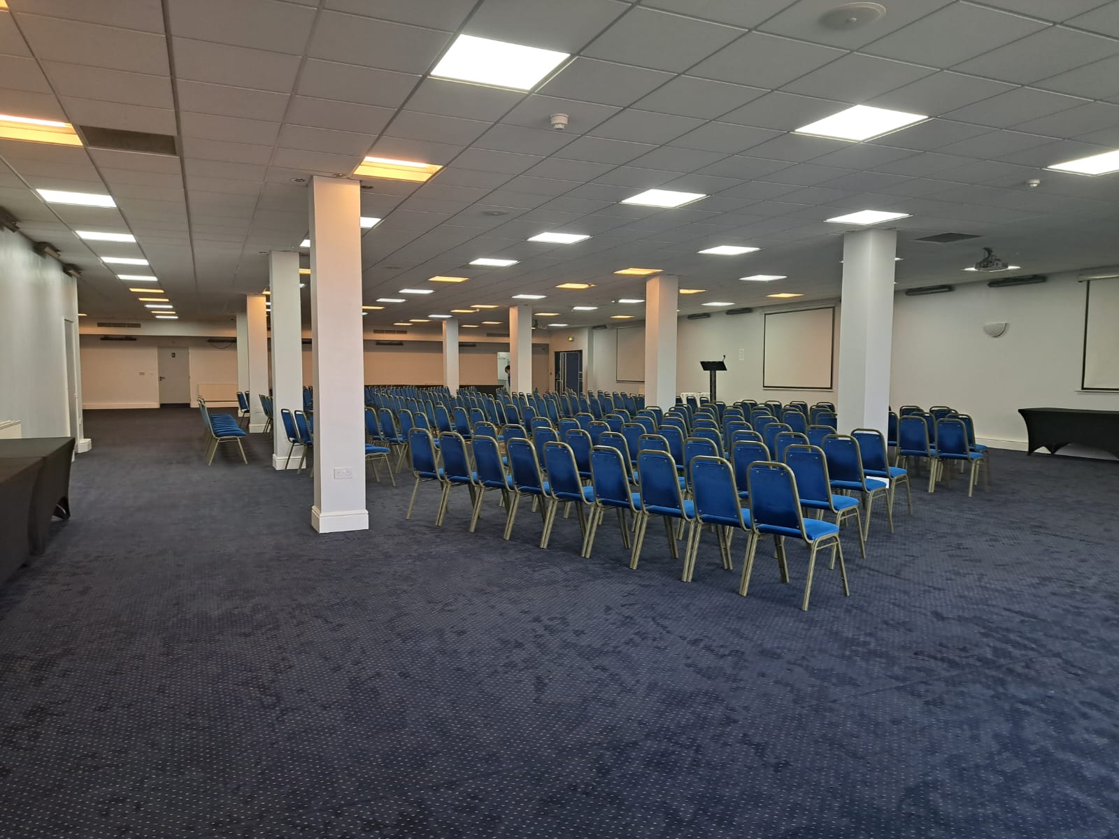 Spacious Saffron Suite conference venue with blue chairs, ideal for seminars and workshops.