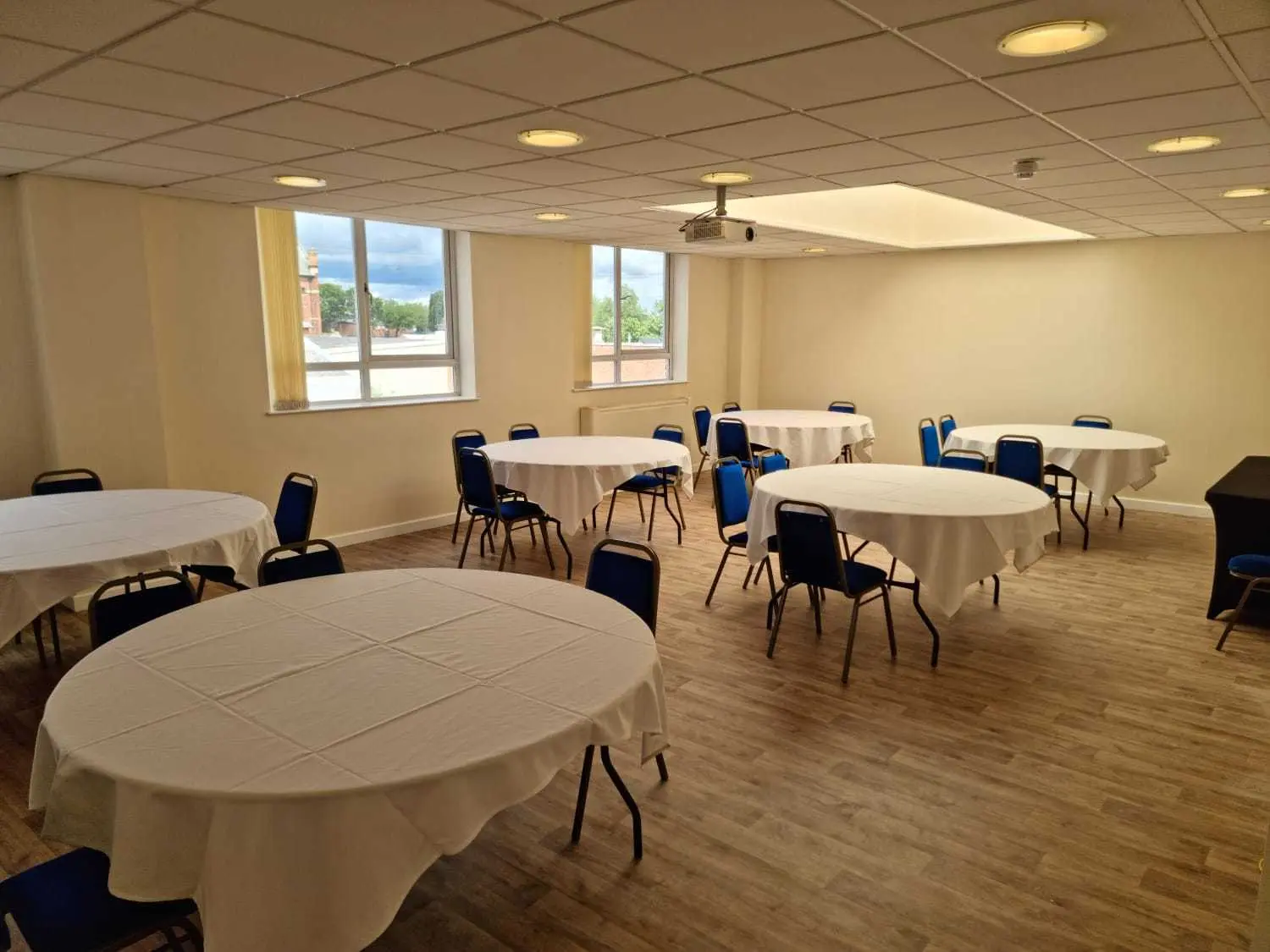 Versatile meeting room with round tables and blue chairs, ideal for workshops and networking.