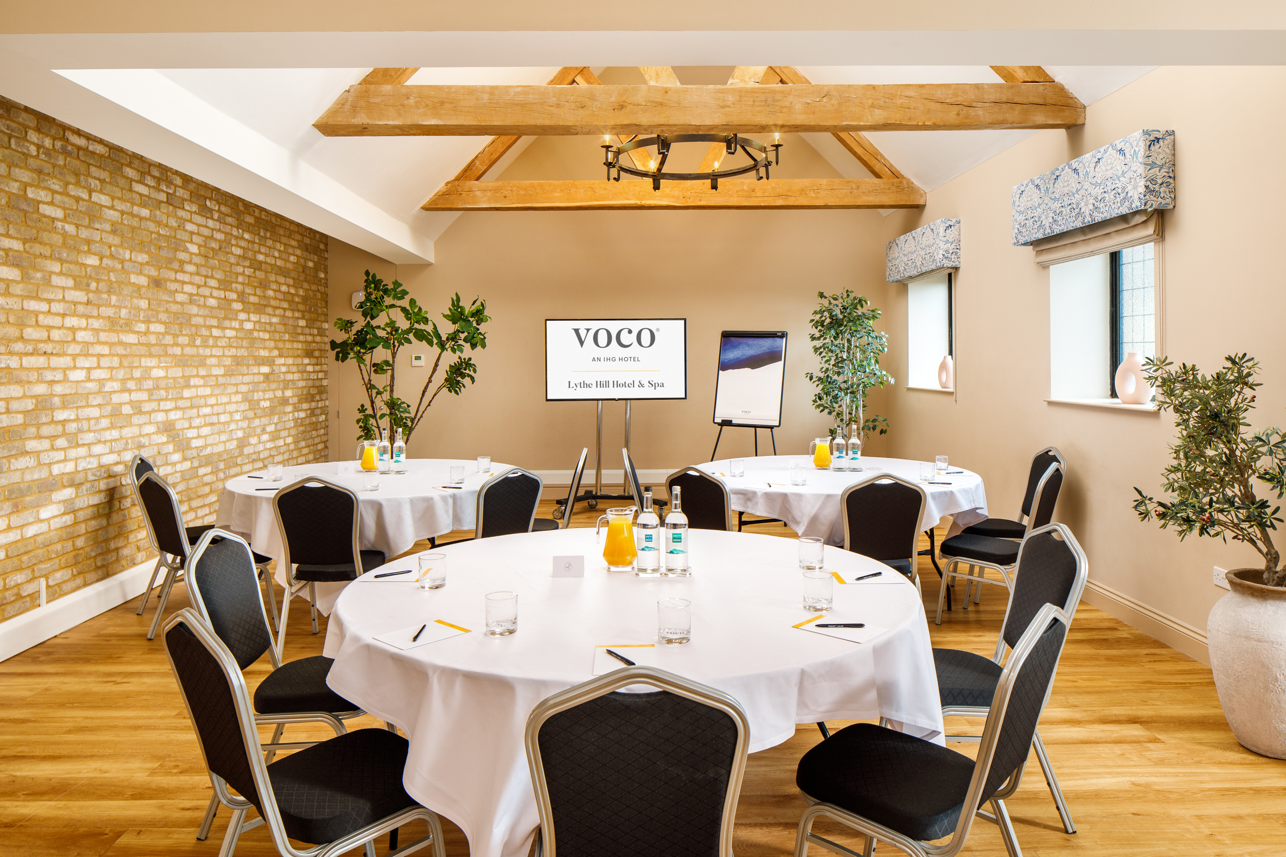 Cedar Suite at Voco Lythe Hill: inviting meeting space with round tables and natural light.