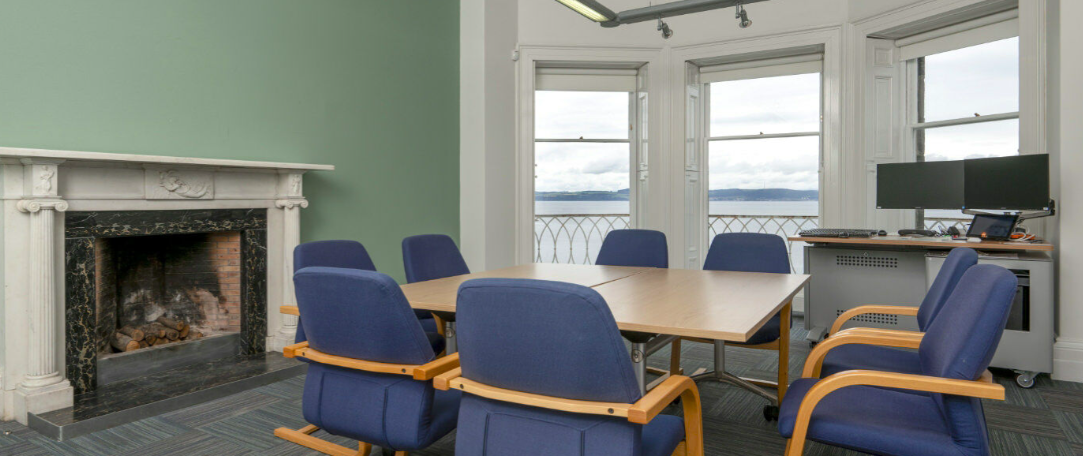 Bright meeting room with large table and blue chairs, perfect for events and brainstorming.