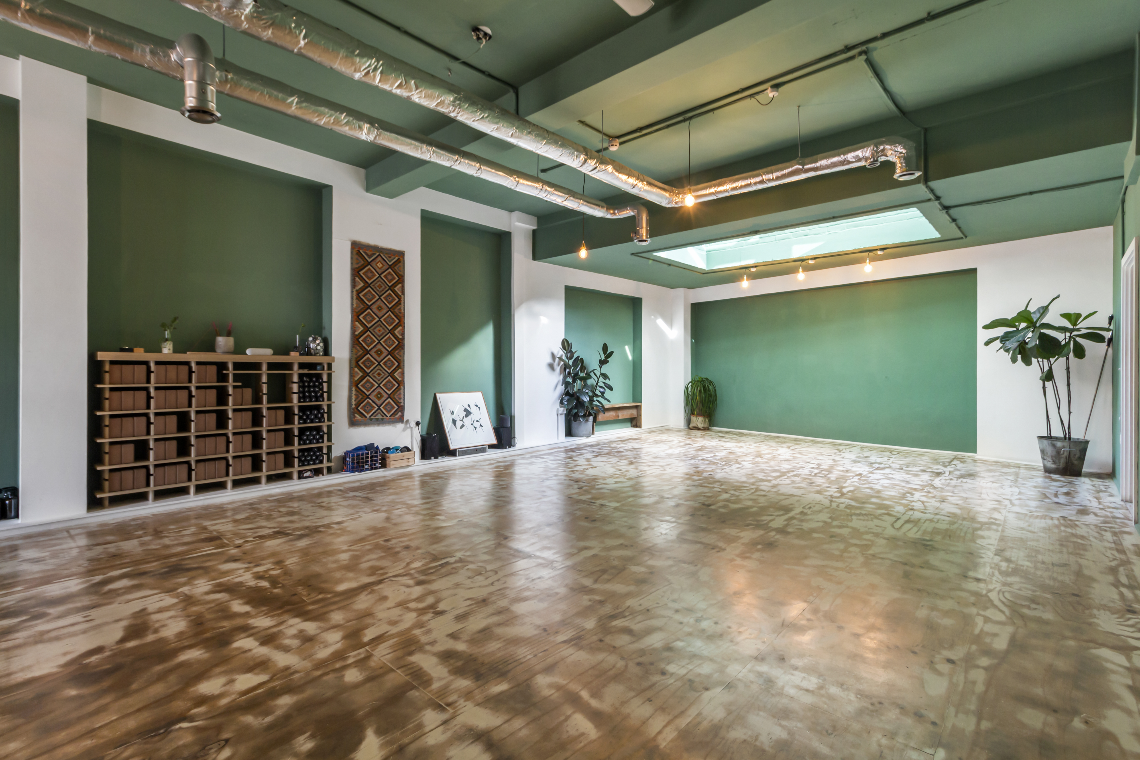 Modern yoga studio with green walls, perfect for workshops and gatherings.