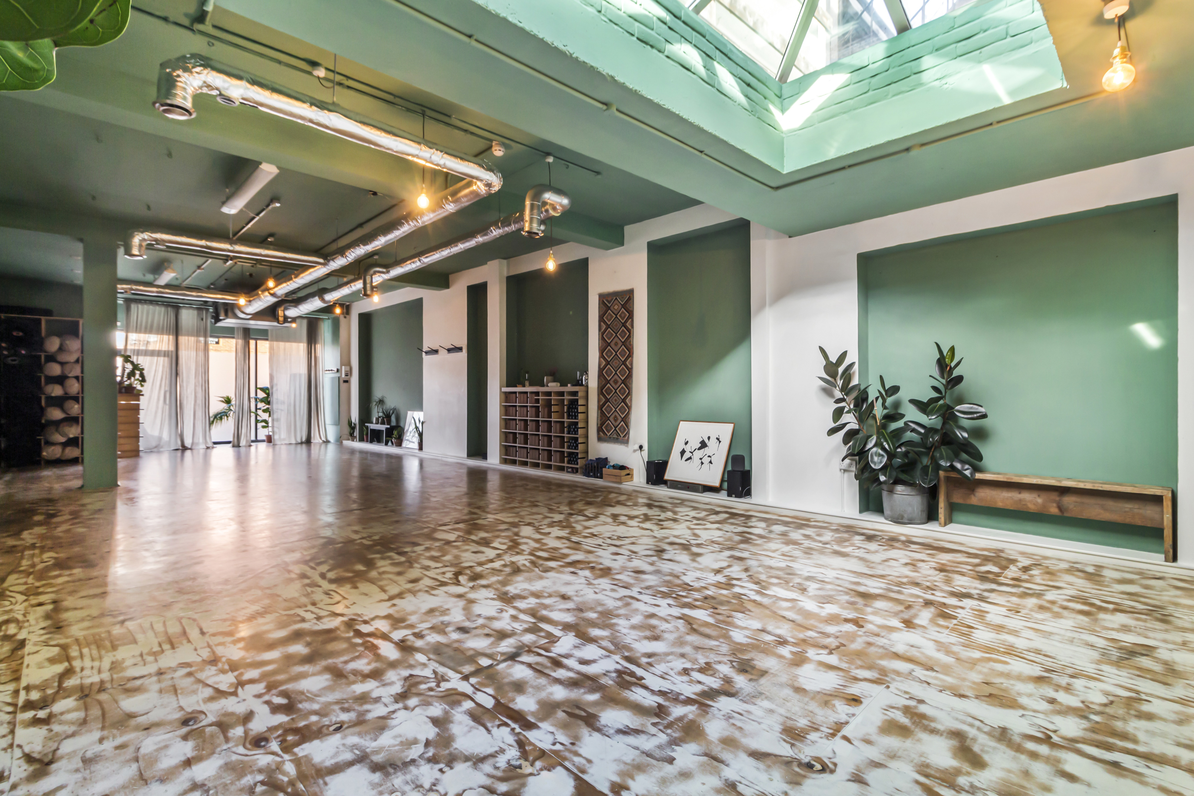 Modern yoga studio with green walls, ideal for workshops and networking events.