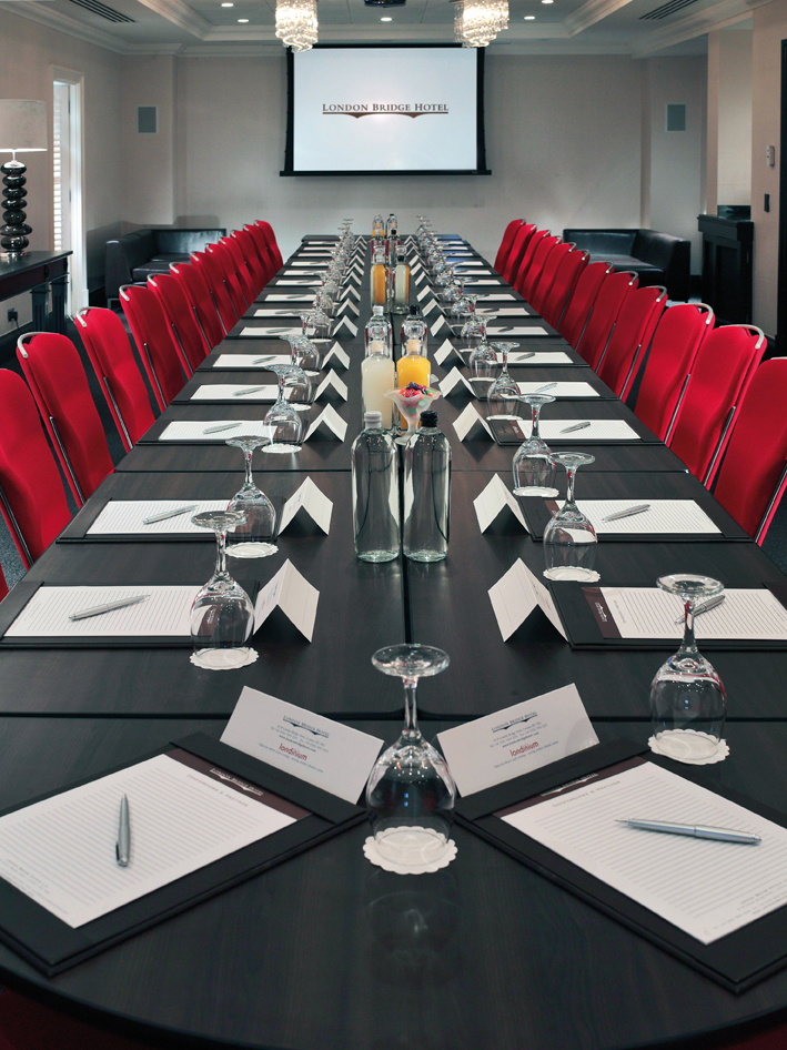 Shakespeare Suite I at London Bridge Hotel, featuring a long table and vibrant red chairs.