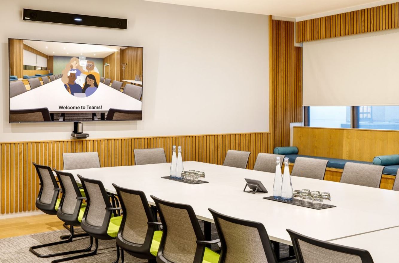 Modern conference room at Mercure Bedford Hotel with ergonomic chairs and tech display.