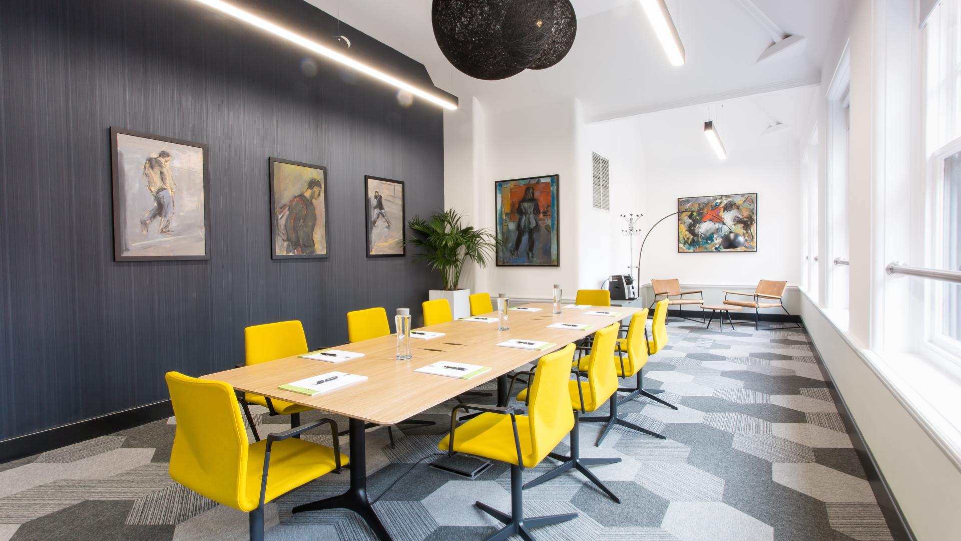Modern meeting room with long table and vibrant yellow chairs for workshops in Whalley Range.