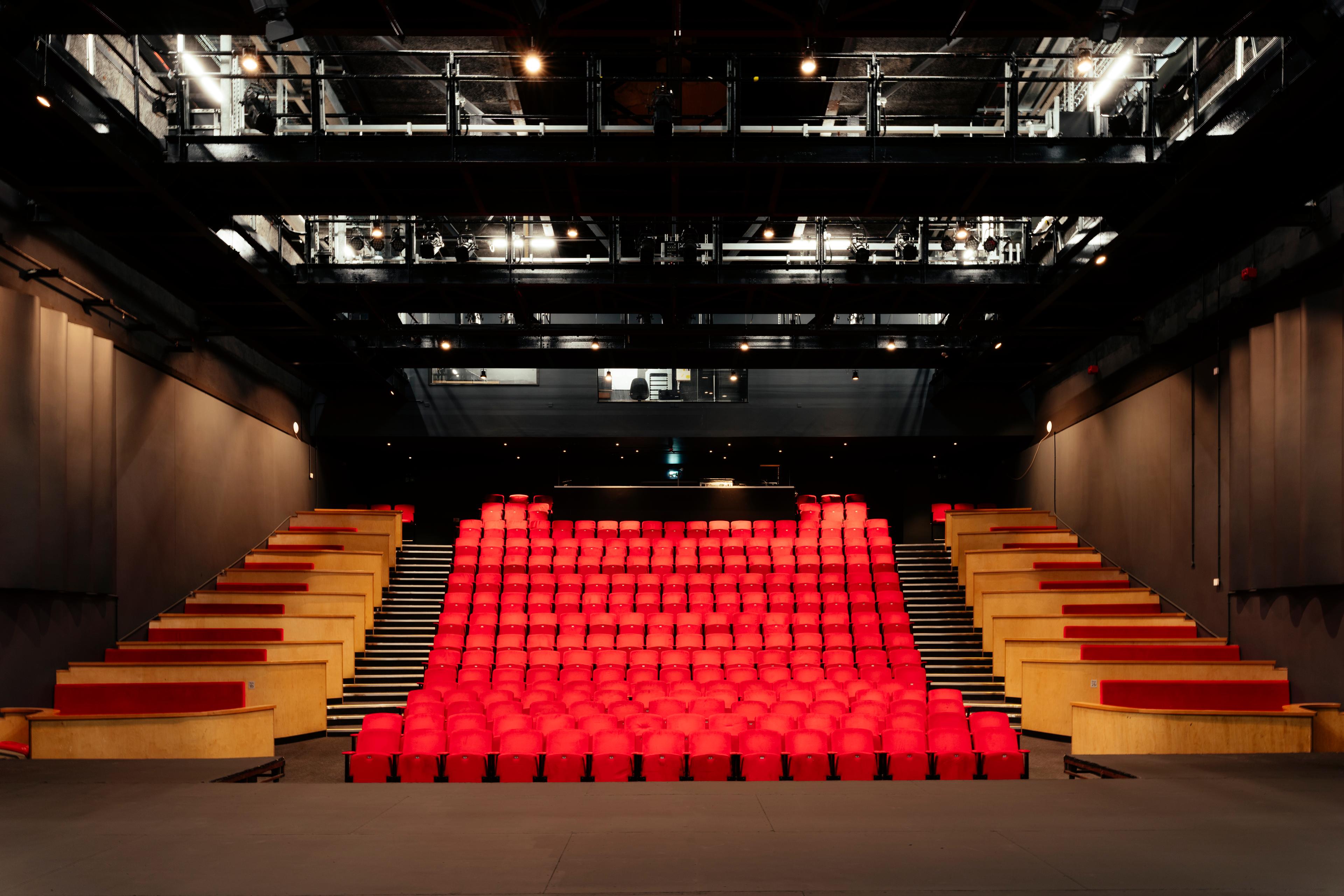 Modern auditorium with vibrant red seating, ideal for conferences and performances.