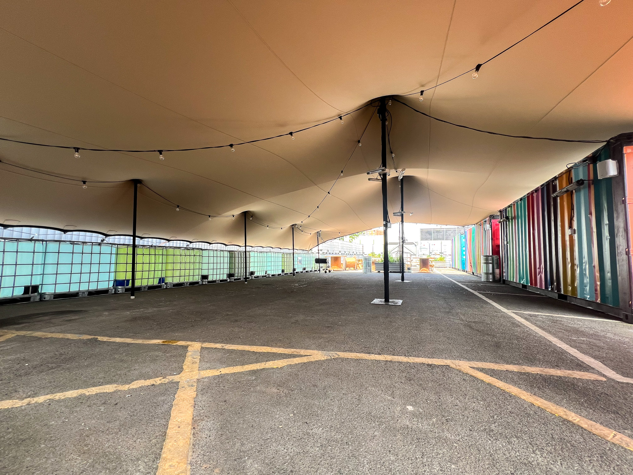 Outdoor event space with fabric canopy and colorful shipping containers for gatherings.
