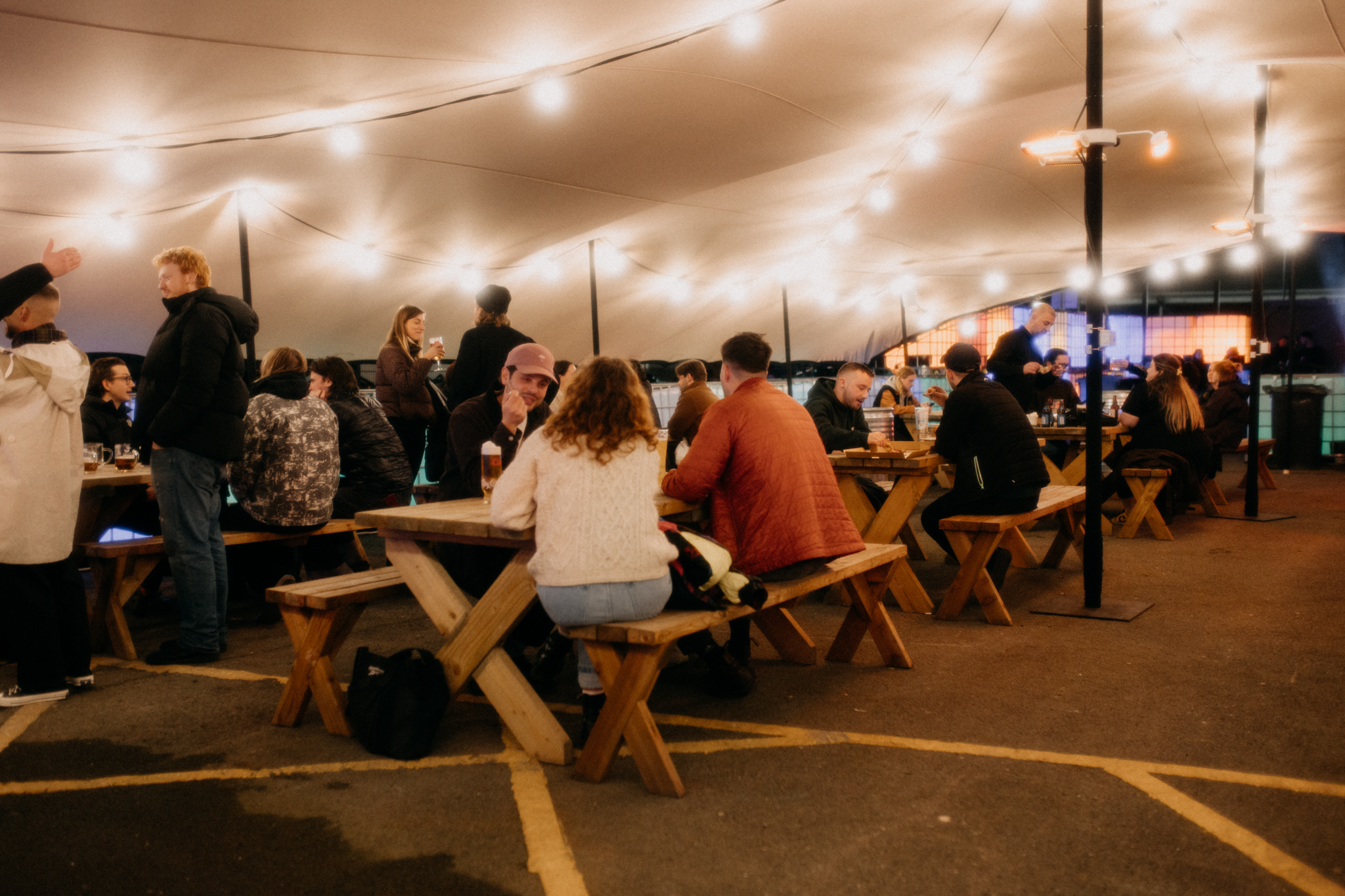 Vibrant outdoor event space with communal seating under string lights for gatherings.