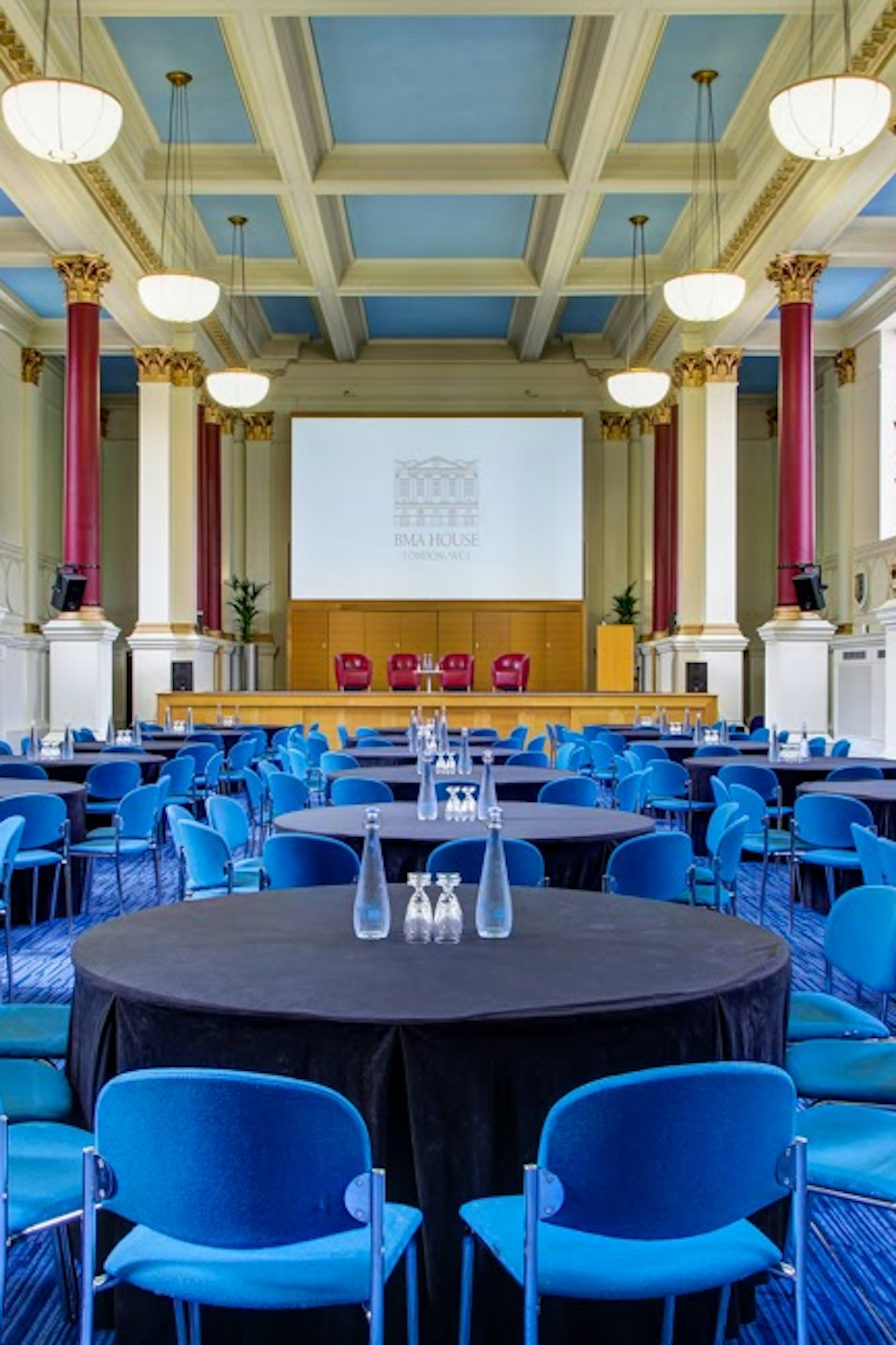 Event space at Tarling East Community Centre with round tables and blue chairs for conferences.