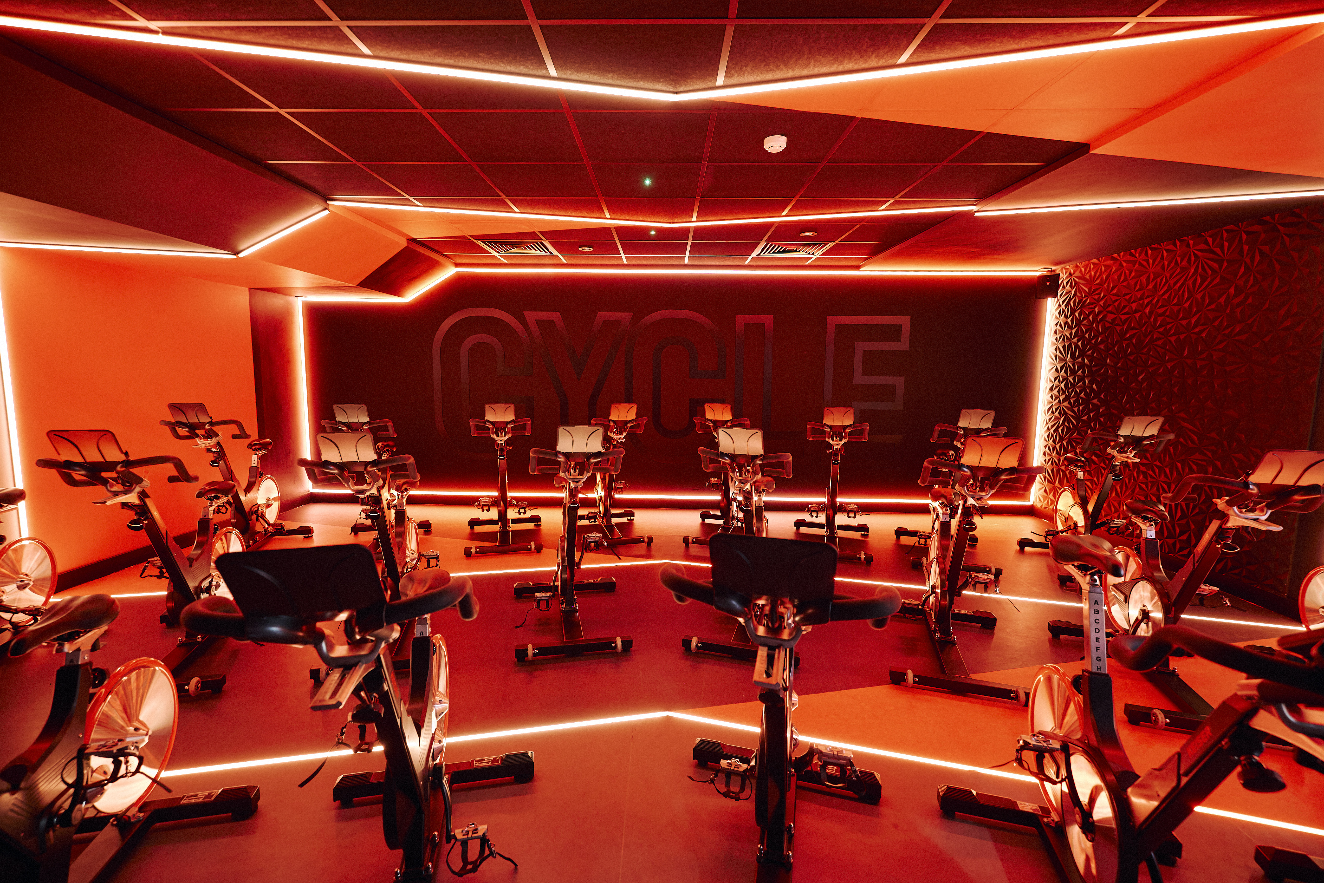 Modern indoor cycling studio with red lighting for wellness retreats and team-building events.