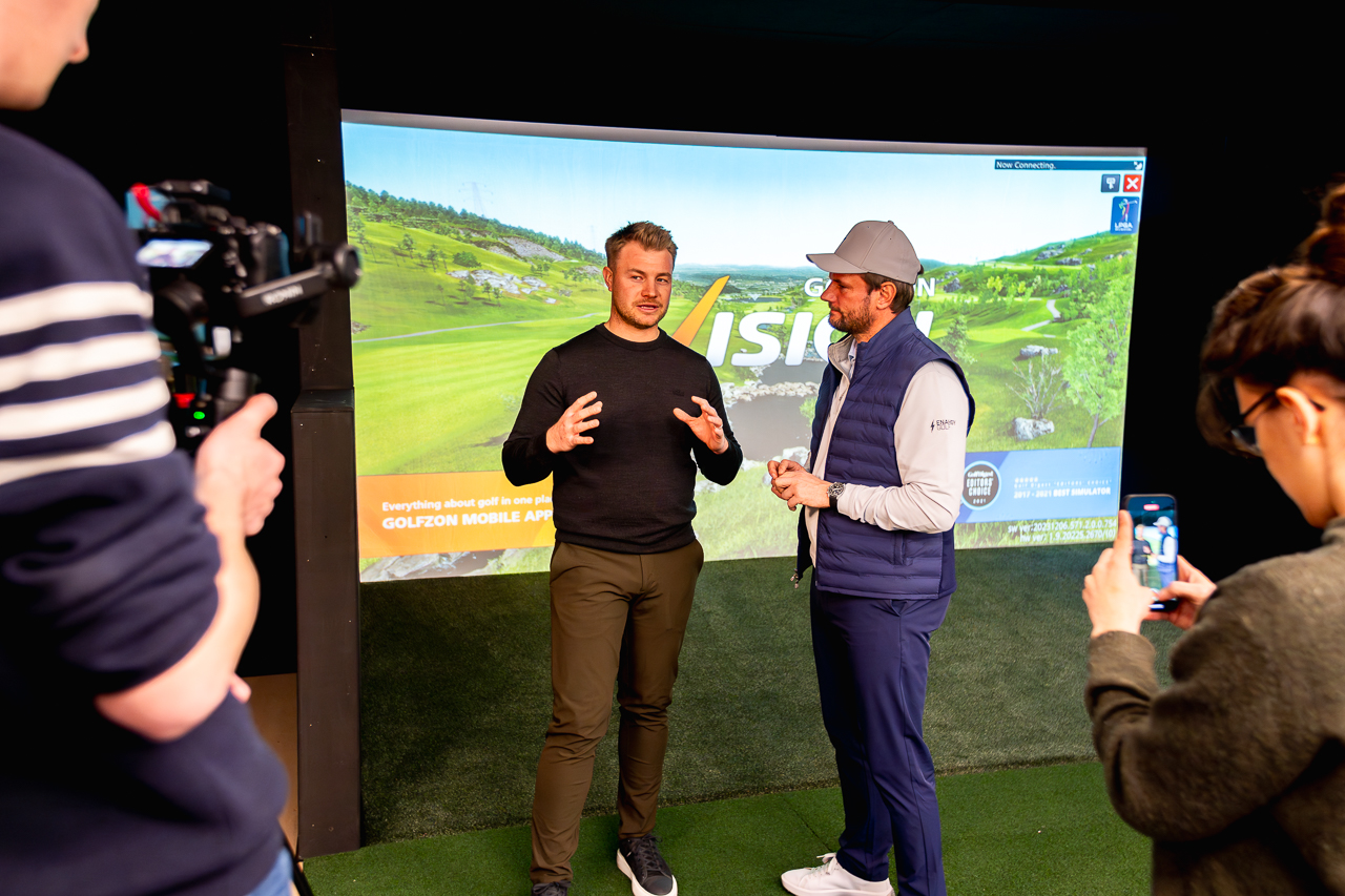 Indoor golf simulators event with speakers, cameras, and audience engagement.