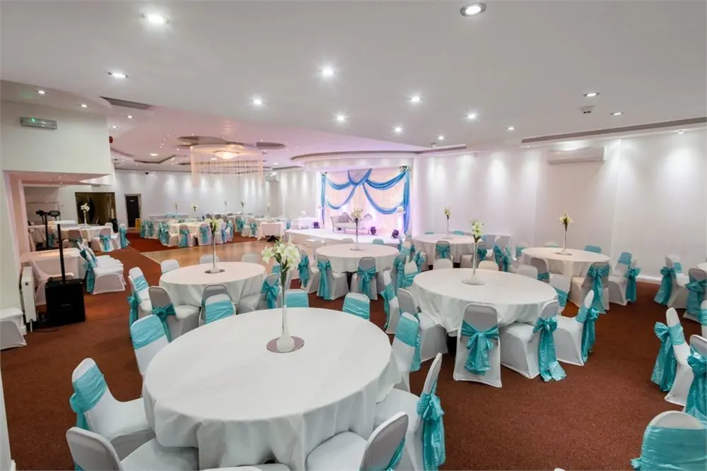 Elegance Banqueting Suite with round tables and aqua blue sashes for weddings and events.