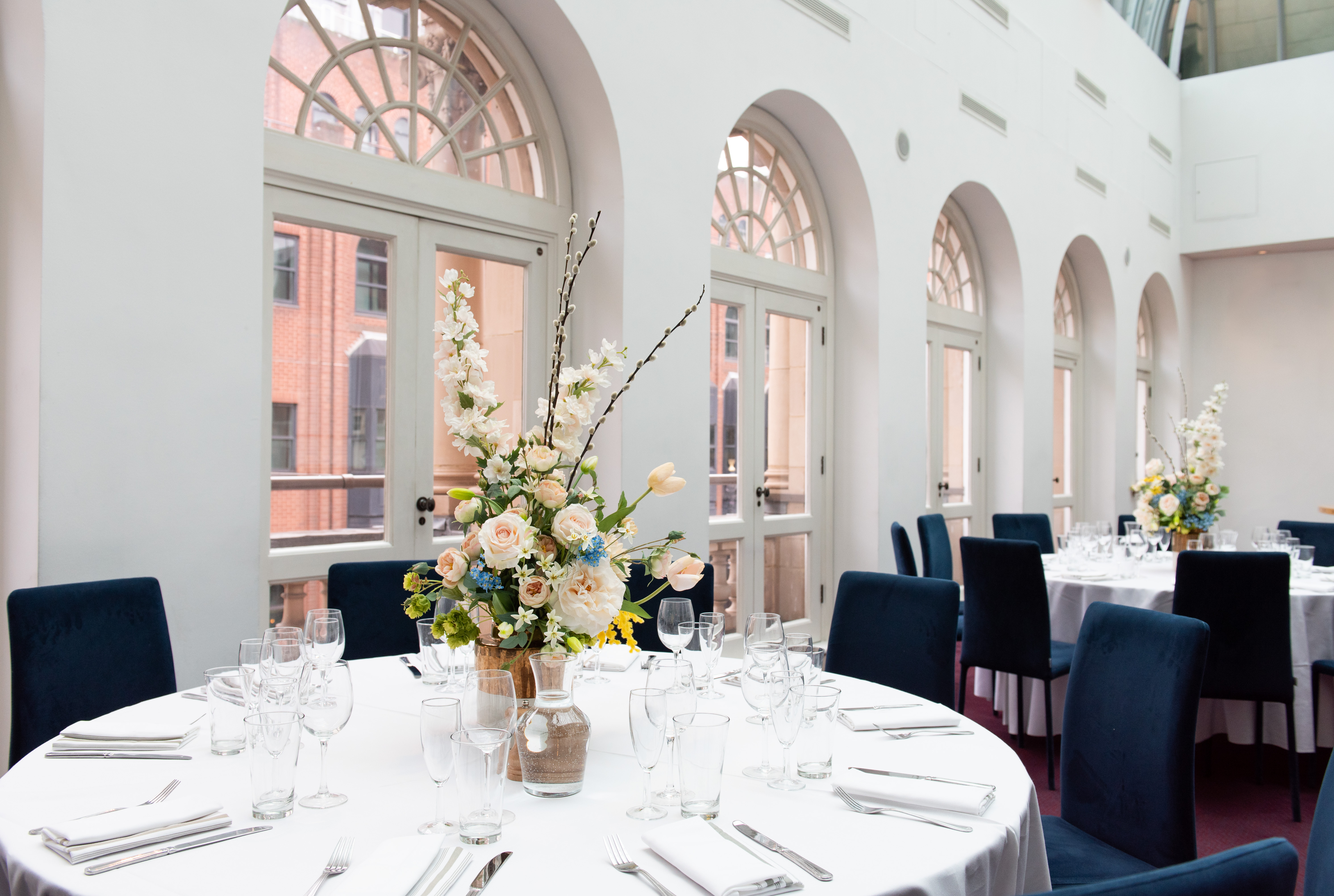 Sky Bar at London Coliseum: elegant event space with round tables and floral centerpieces.