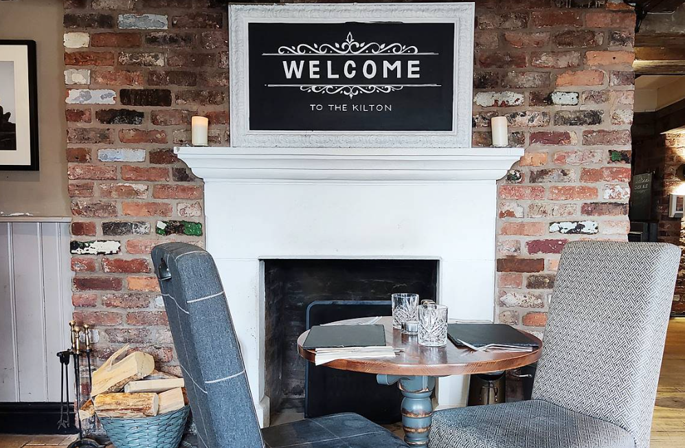 Cozy meeting space at The Kilton Inn with rustic brick wall and fireplace, ideal for networking.