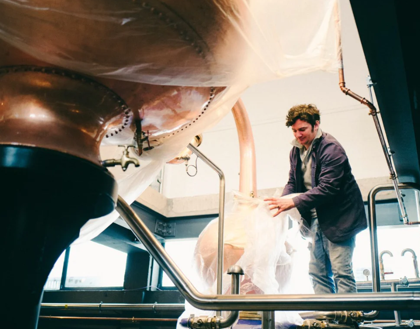 Professional preparing brewing equipment in modern Burnt Faith Brandy House for craft beer events.