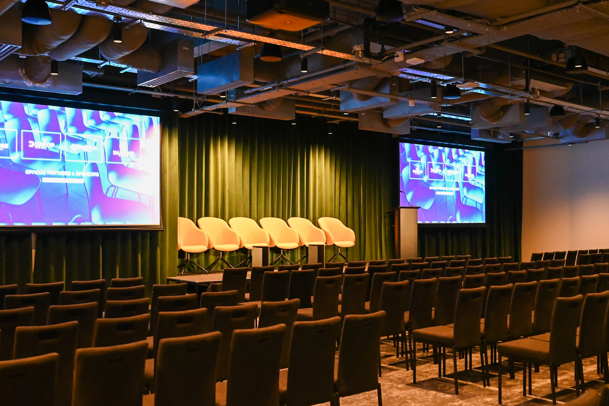 Minster Forum event space with stage, screens, and seating for presentations.