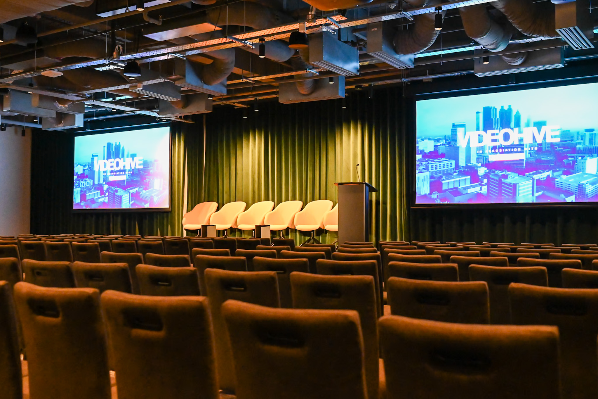 Minster Forum event space with stage, screens, and seating for presentations and networking.