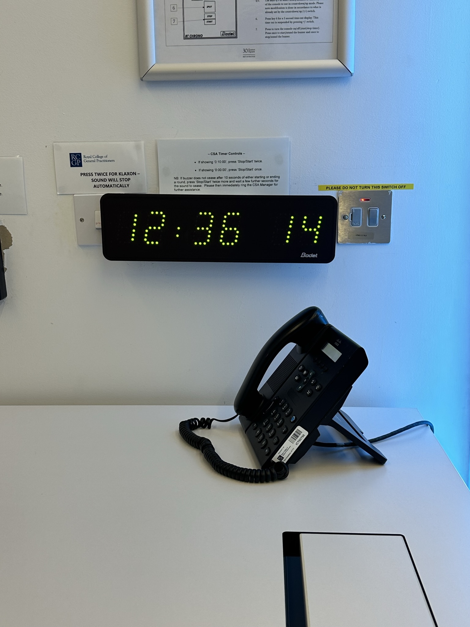 Digital clock and conference phone in meeting space at Scenario Assessment Centre, Euston Square.