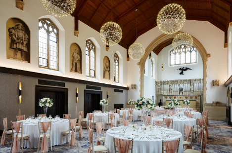 Elegant event space at Poles Hall, Hanbury Manor with pink accents and chandeliers.