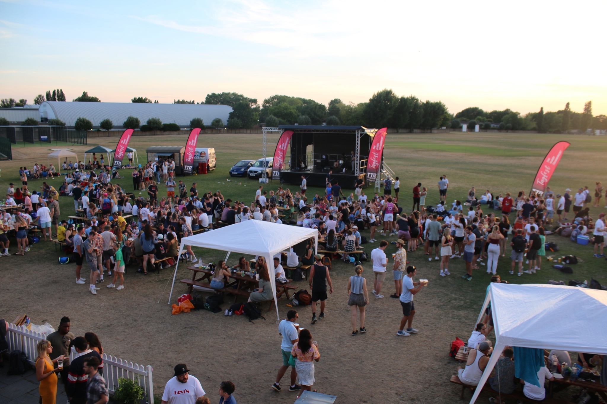 Vibrant outdoor event at King's House School with large crowd and tents for networking.
