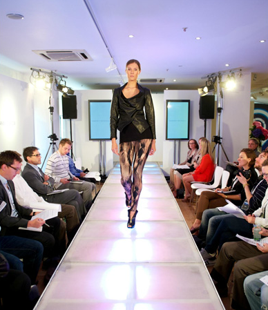 Fashion runway event at OXO2 with model showcasing latest designs and audience engagement.
