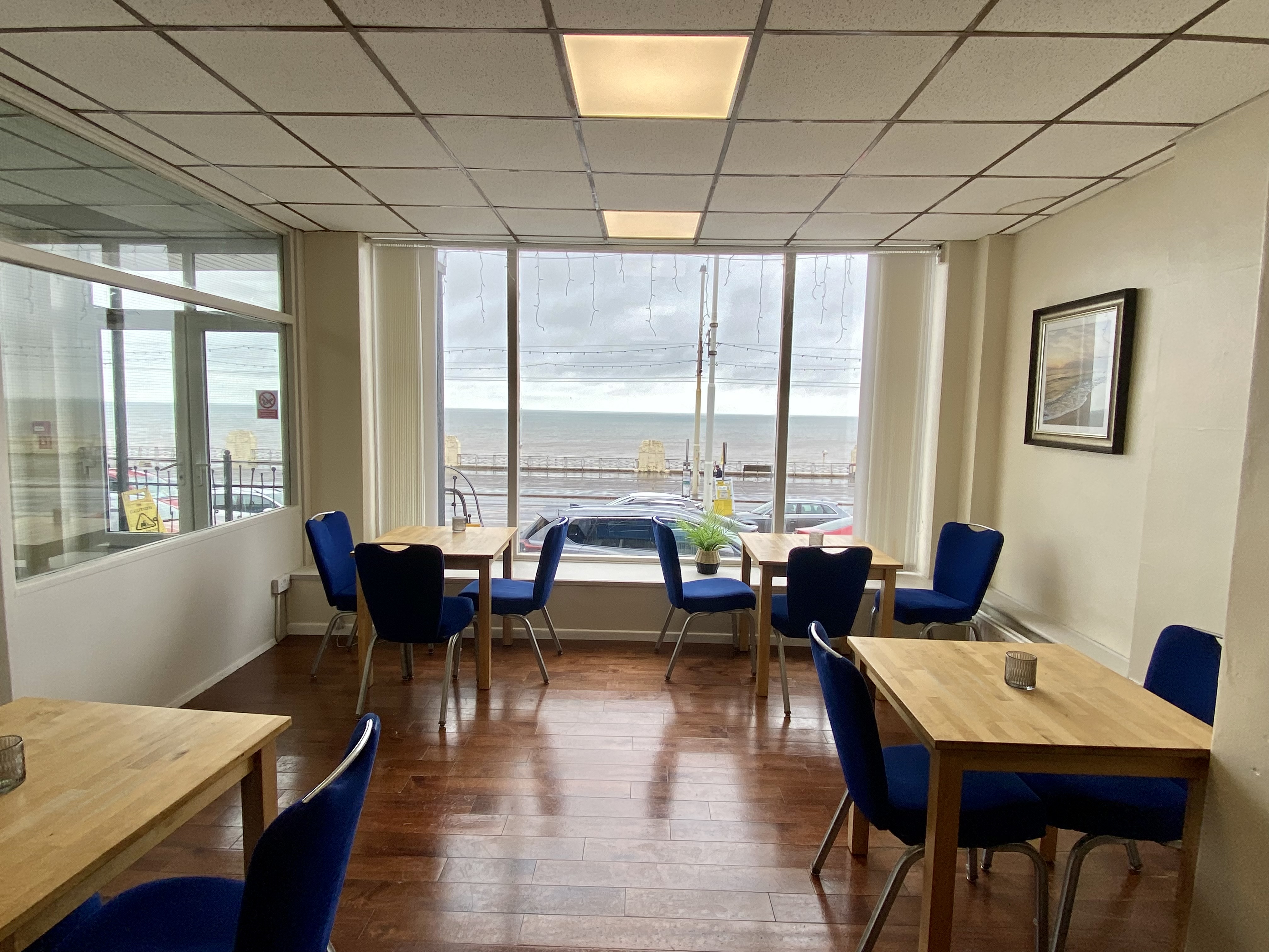 Bright meeting room with sea view, wooden tables, ideal for informal gatherings.