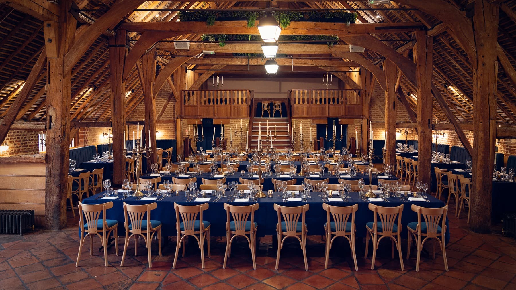 Rustic Fairfax Barn wedding reception with timber frame and navy banquet tables at Leeds Castle.