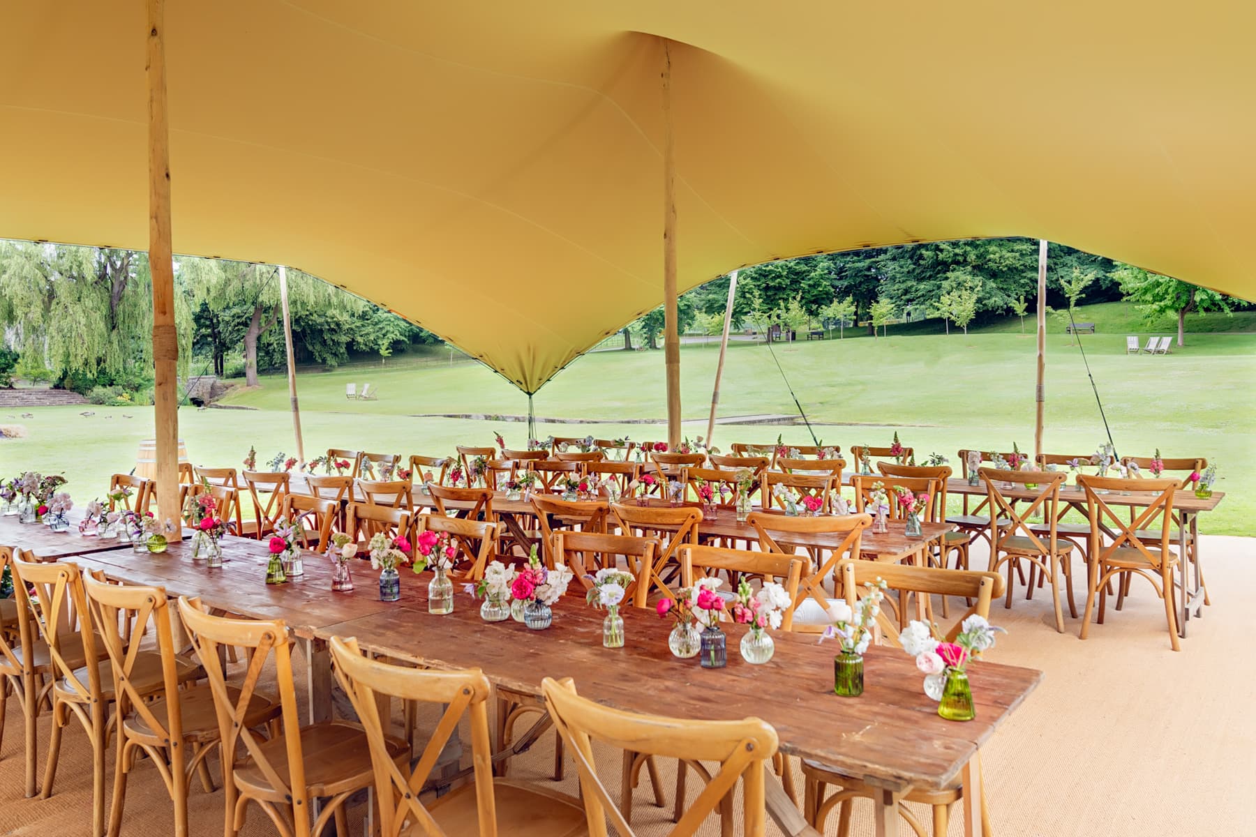 Stretch tent wedding marquee at Leeds Castle with rustic farm tables and floral decor.