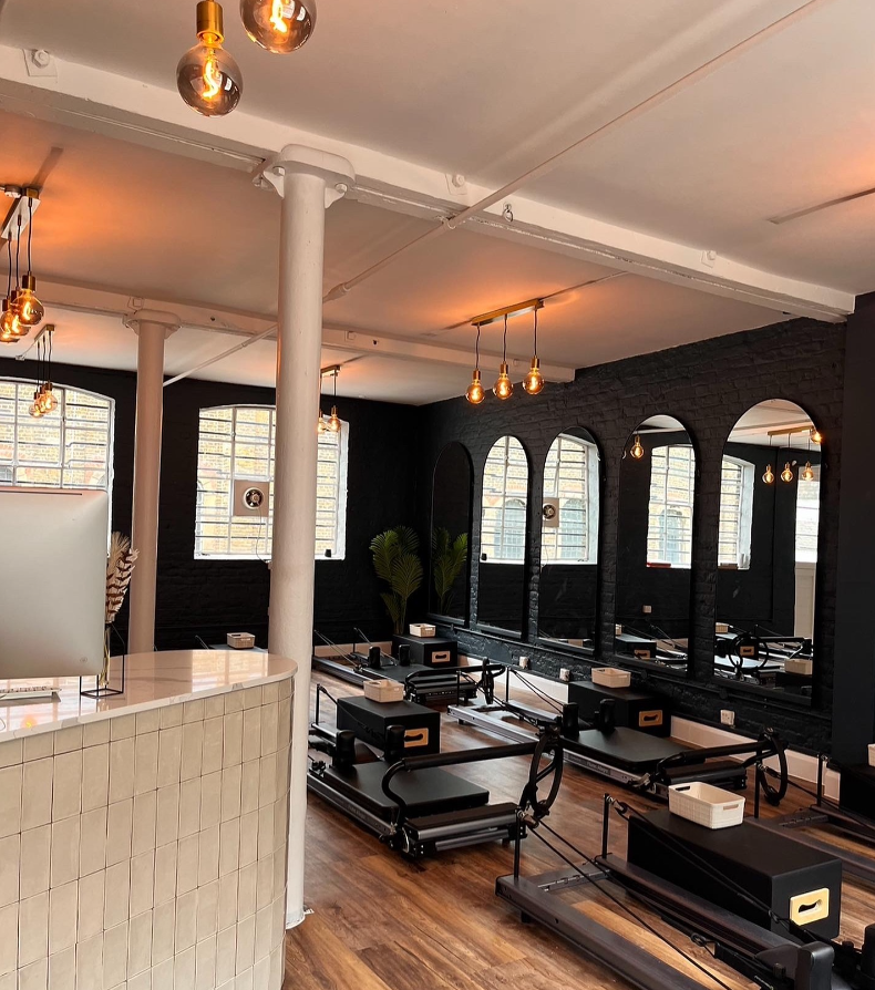 Modern Pilates studio with black walls and arched mirrors, perfect for workshops and events.