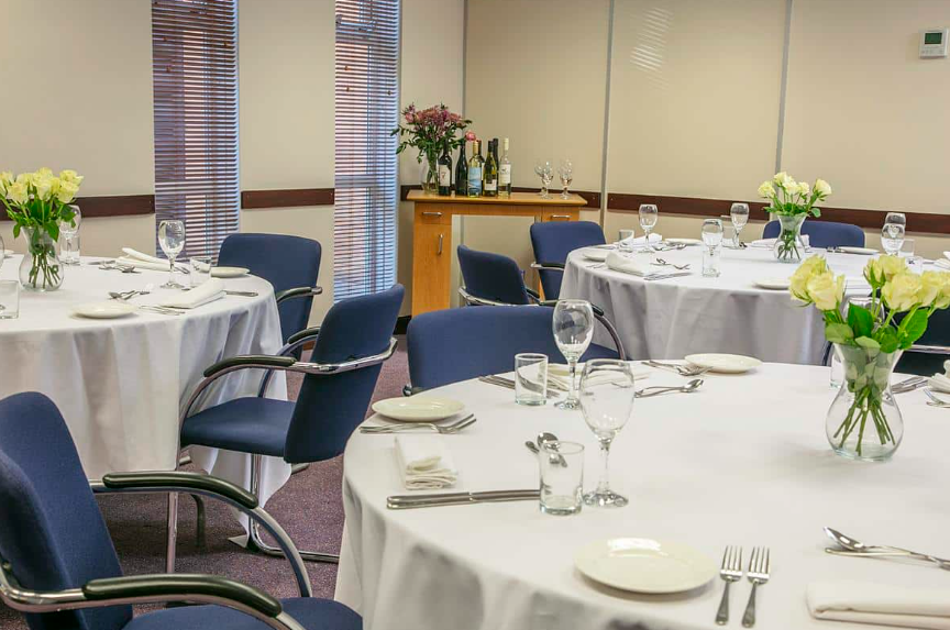 Meetings setup at The Milestone Hotel with elegant round tables and floral centerpieces.