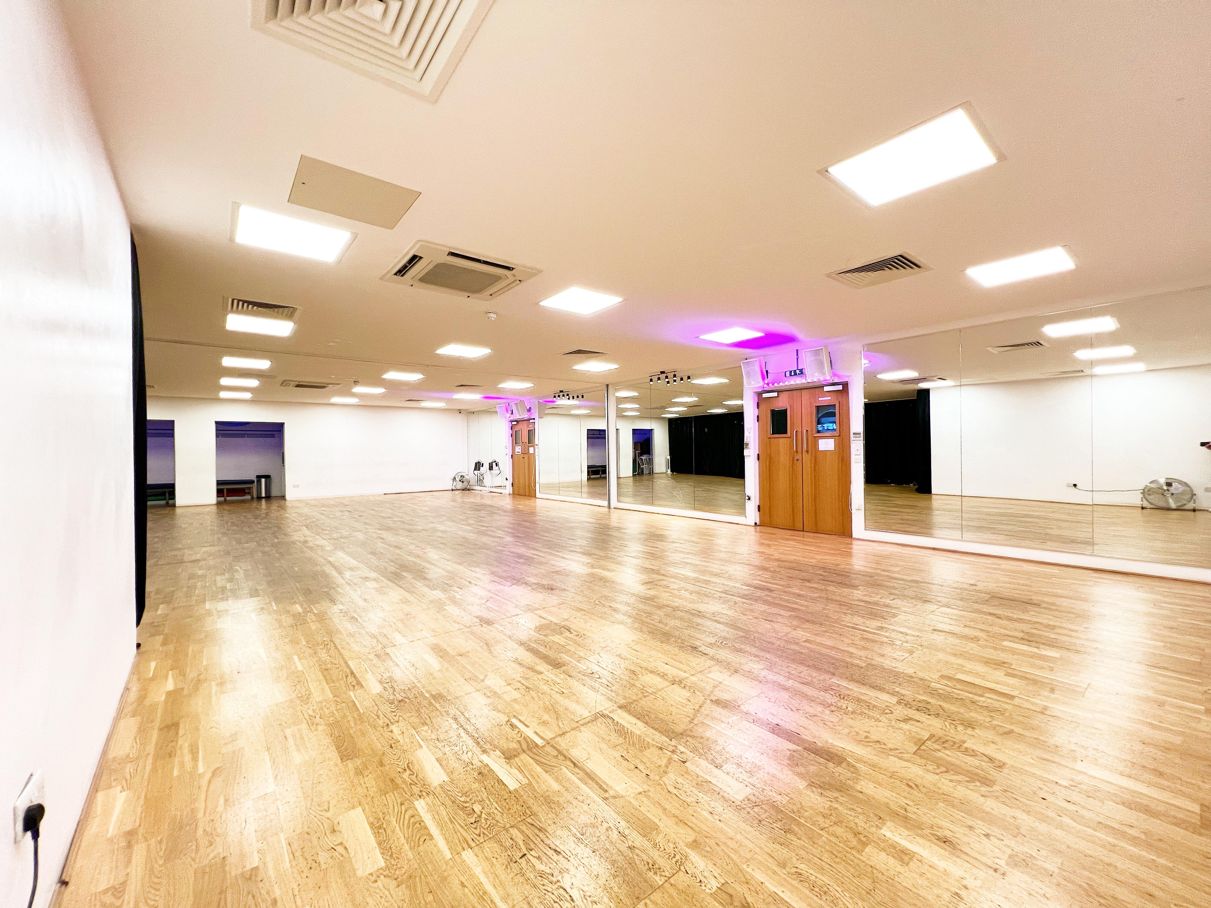 Versatile event space with polished wooden floors, ideal for workshops and fitness classes.