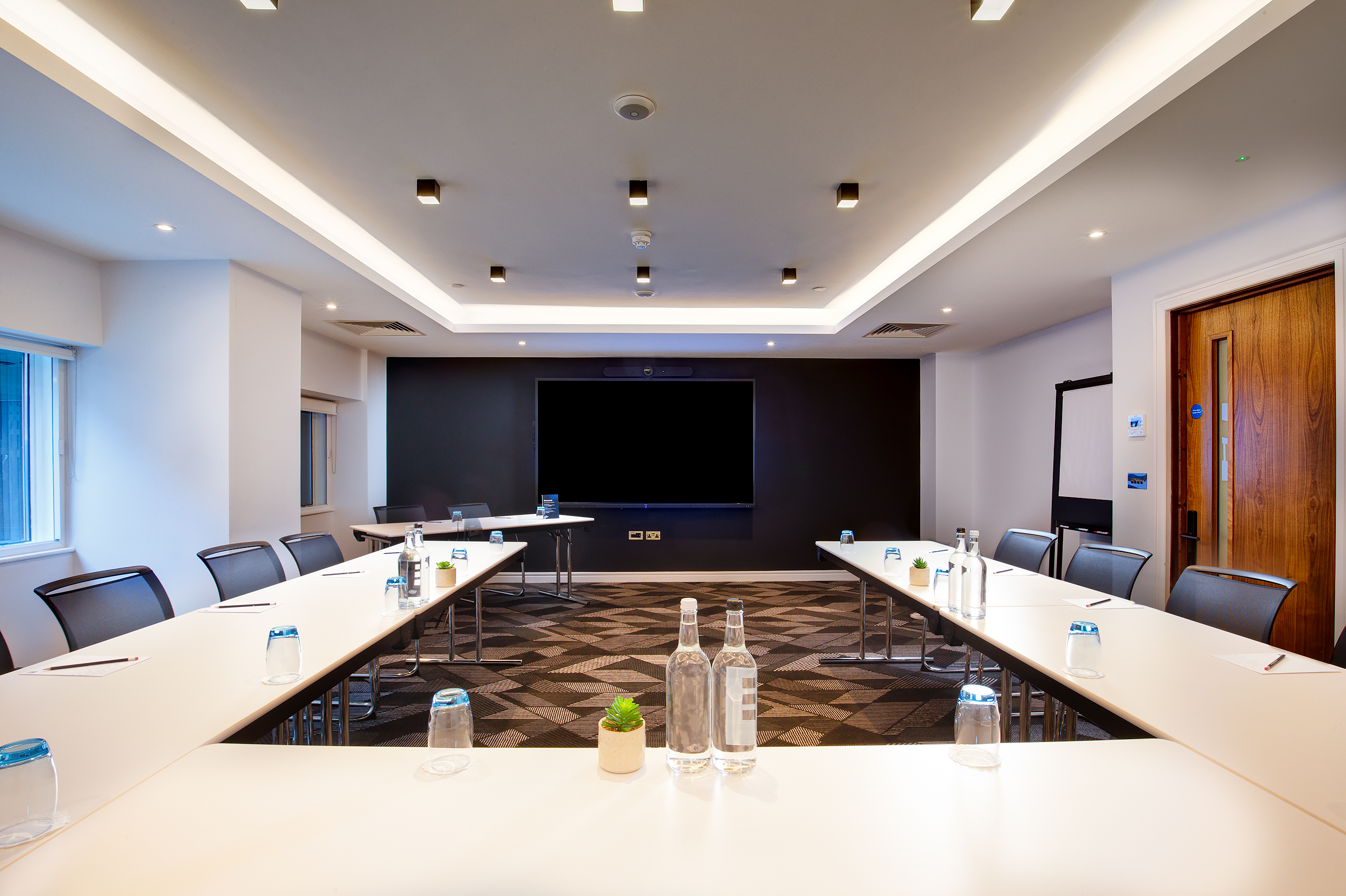 Modern meeting room at Royal National Hotel with U-shaped table for collaborative events.