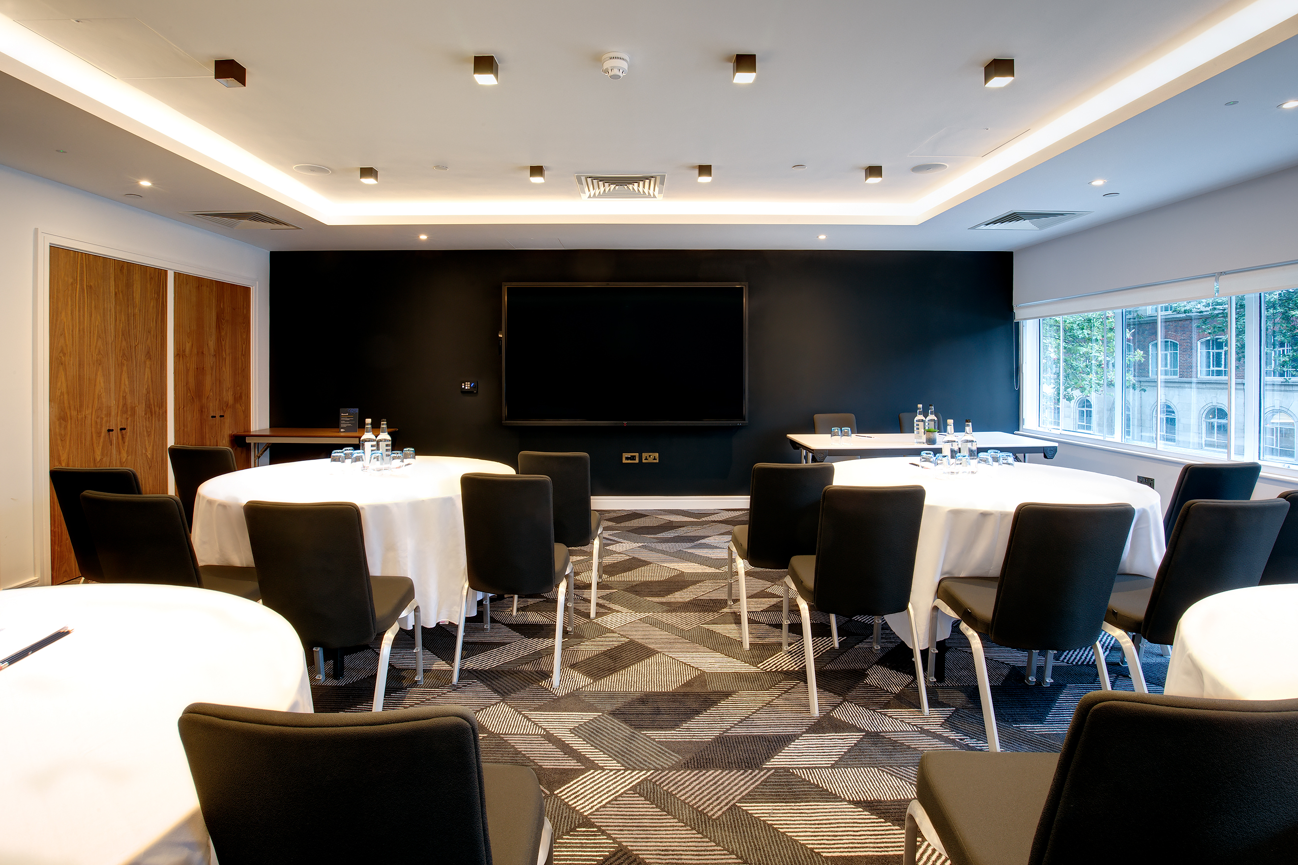 Modern meeting room at Royal National Hotel with circular tables for corporate workshops.