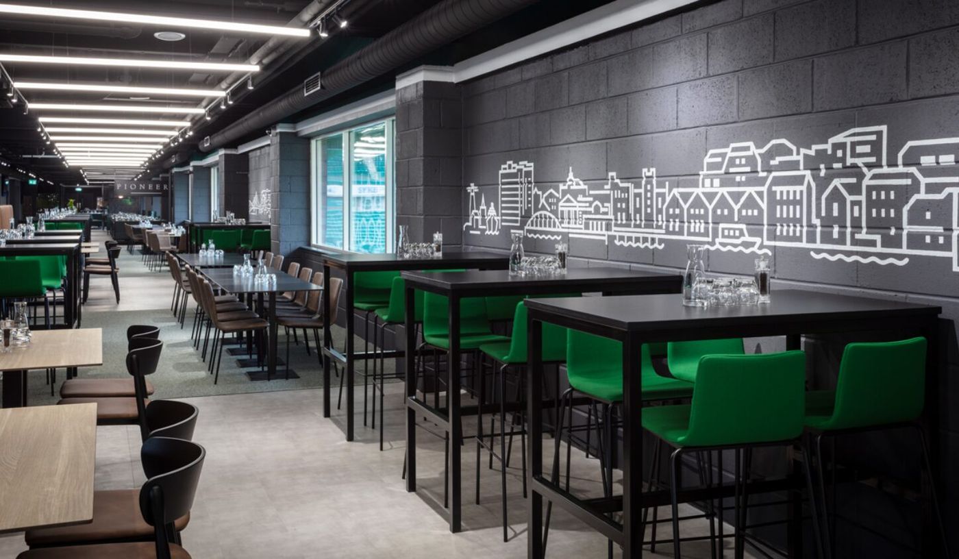 Modern event space at Edinburgh Club, featuring high tables and green chairs for networking.