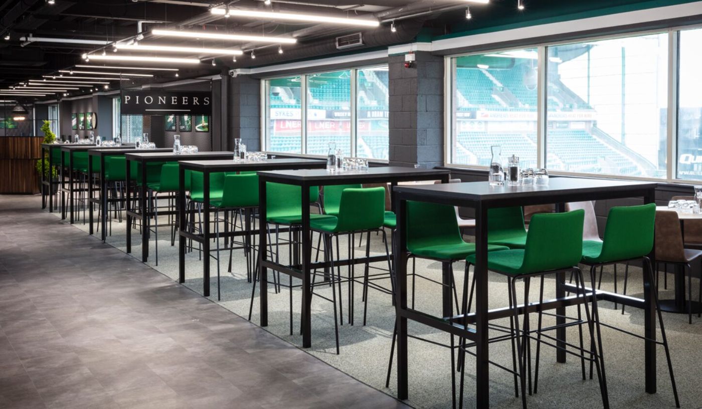 Modern event space at Edinburgh Club, featuring high tables and green chairs for networking.