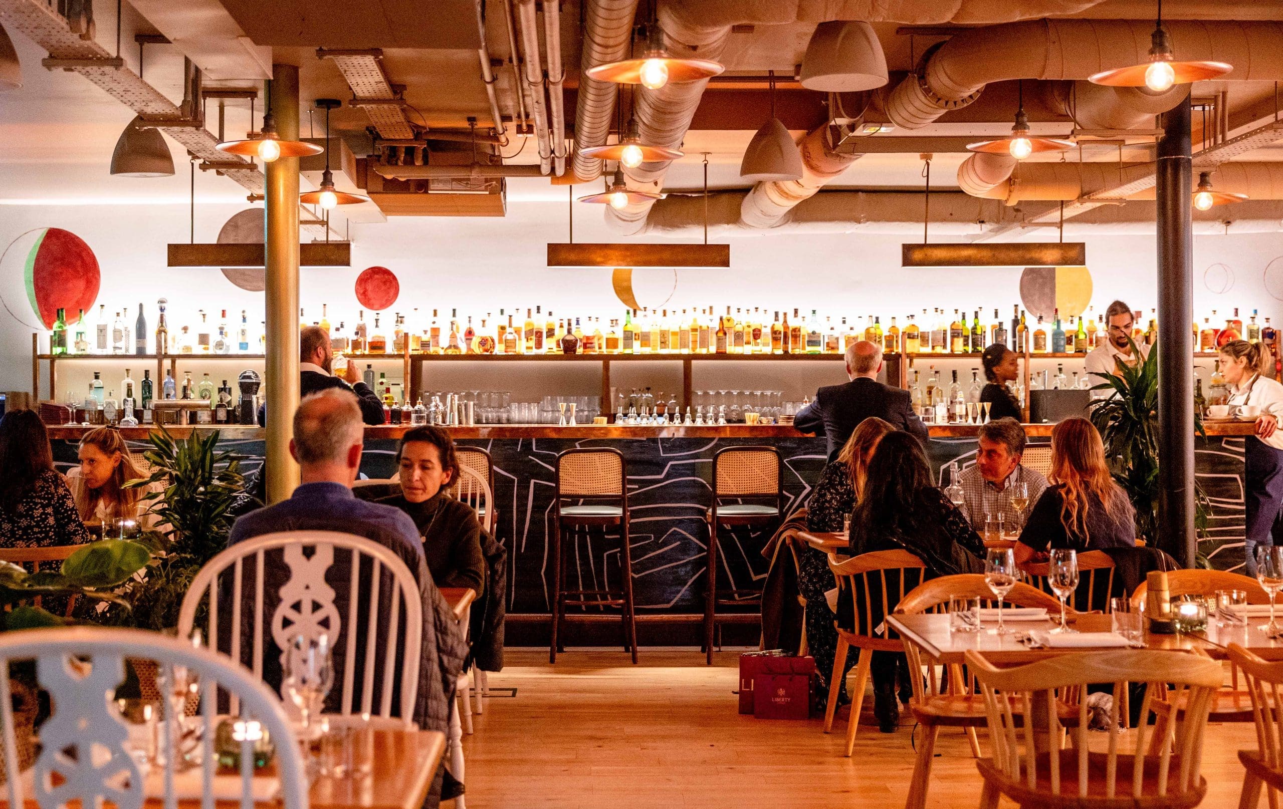 Rooftop restaurant bar with warm lighting, ideal for gatherings and networking events.