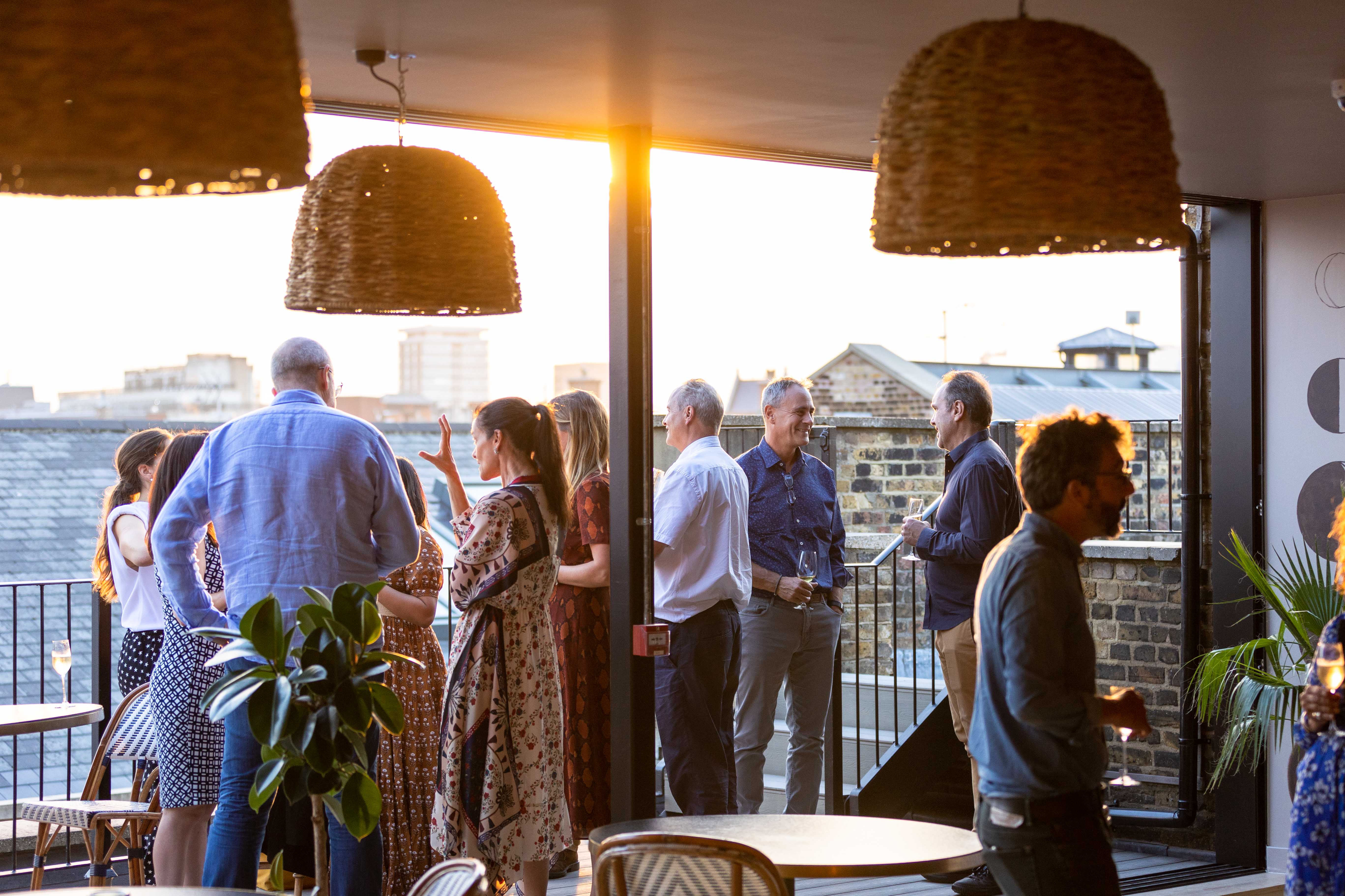 Rooftop networking event at Pergola + Terrace with sunset backdrop and casual attire.