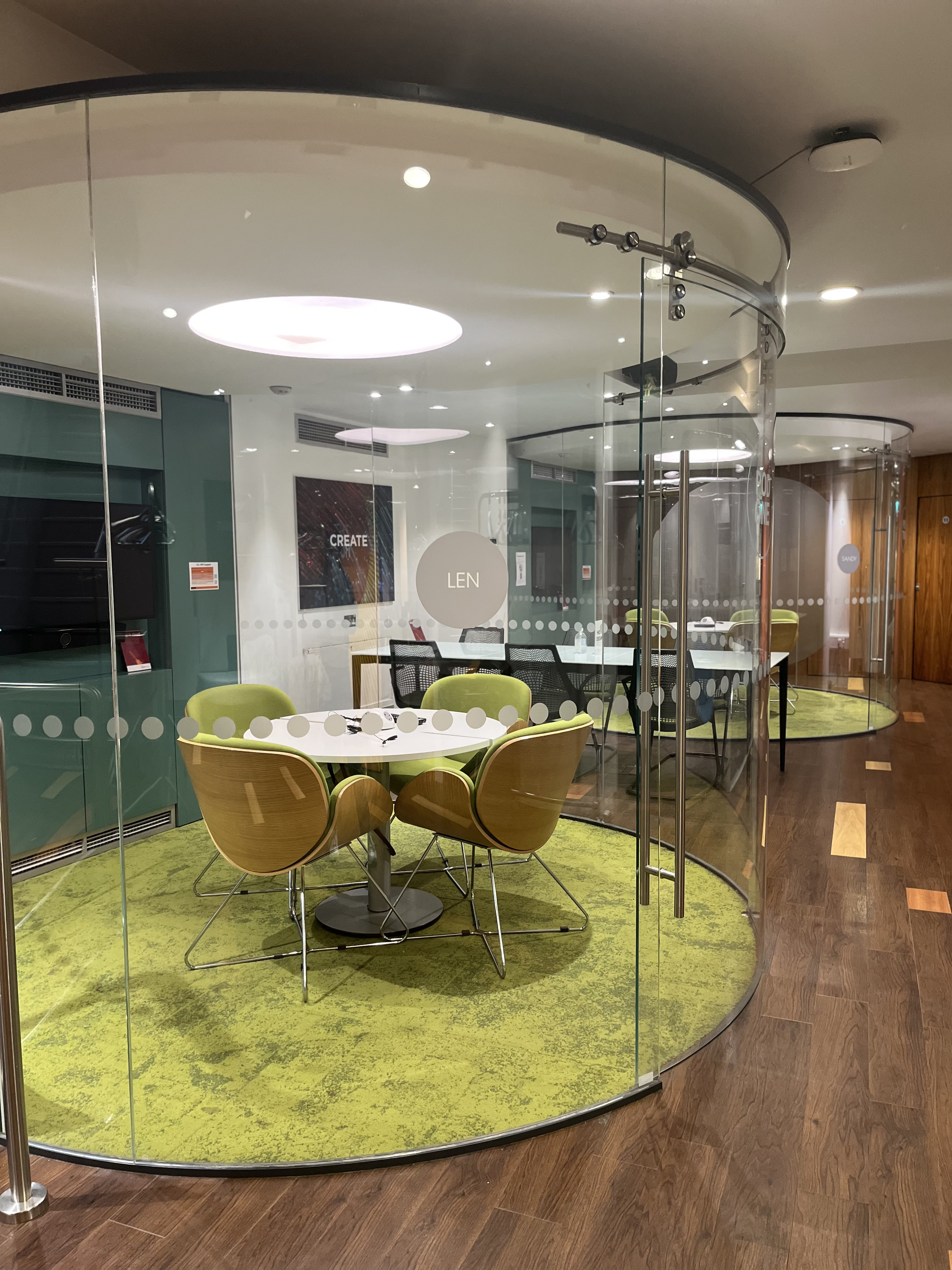 Modern meeting space with round table and green carpet at IDEALondon for collaborative events.