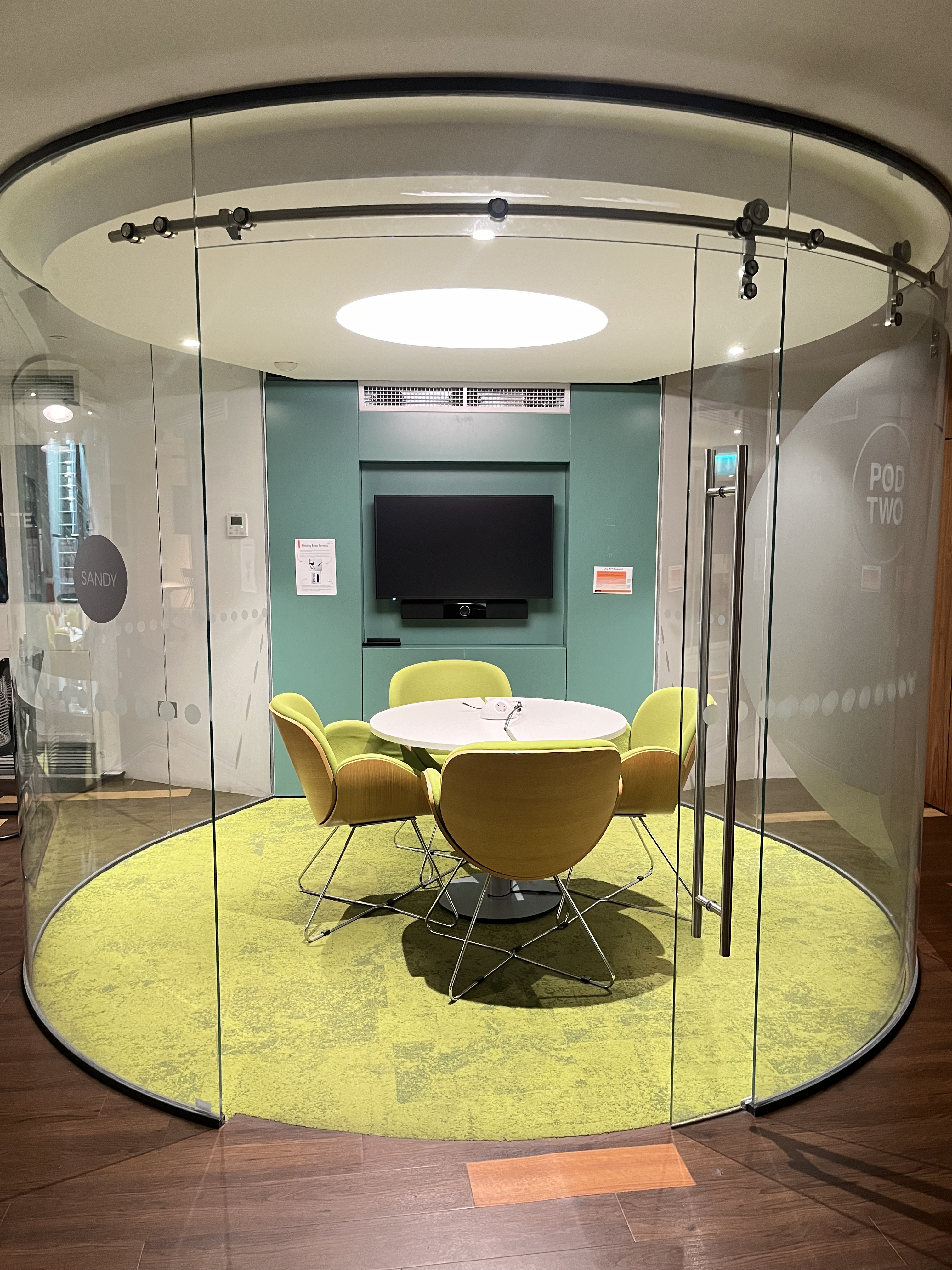 Modern meeting space with round table and green chairs for collaborative events.