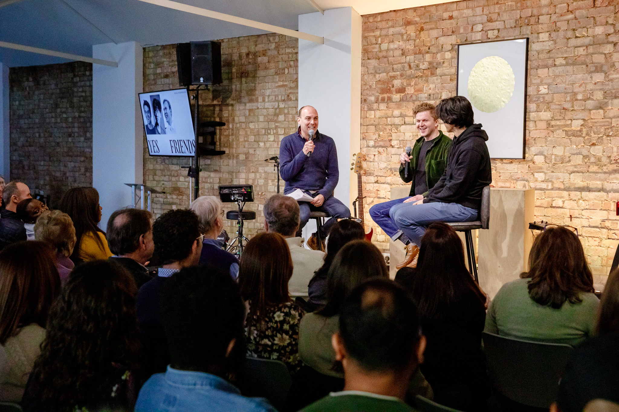 Hybrid event panel discussion with live music in a rustic venue.