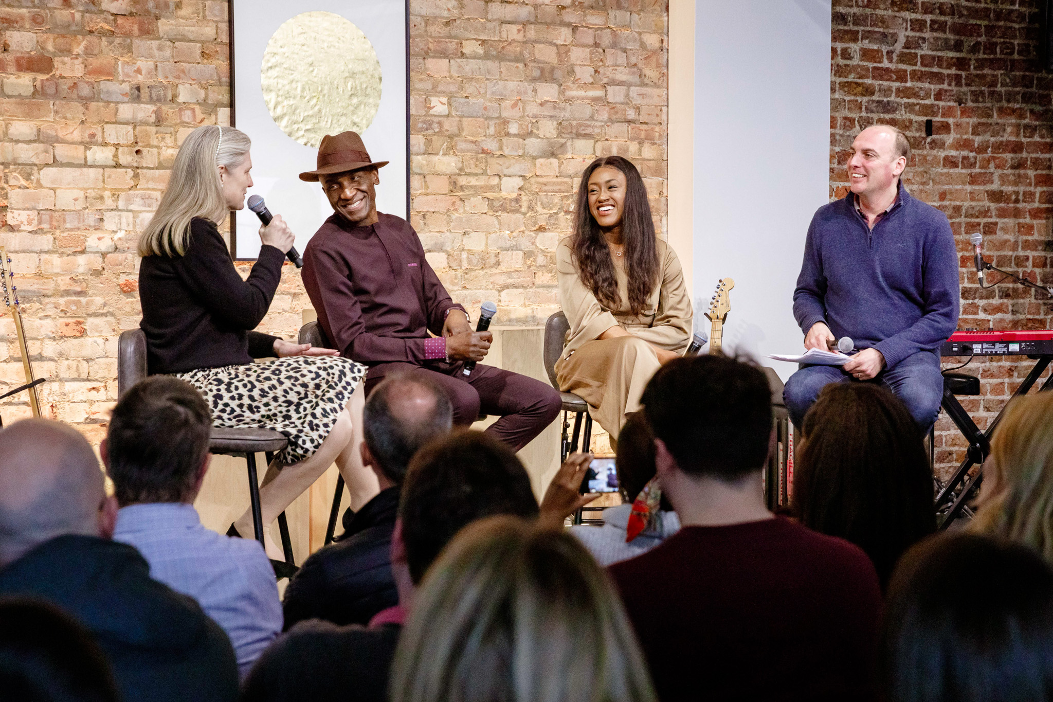 Hybrid event panel discussion with live music in a warm, inviting atmosphere.